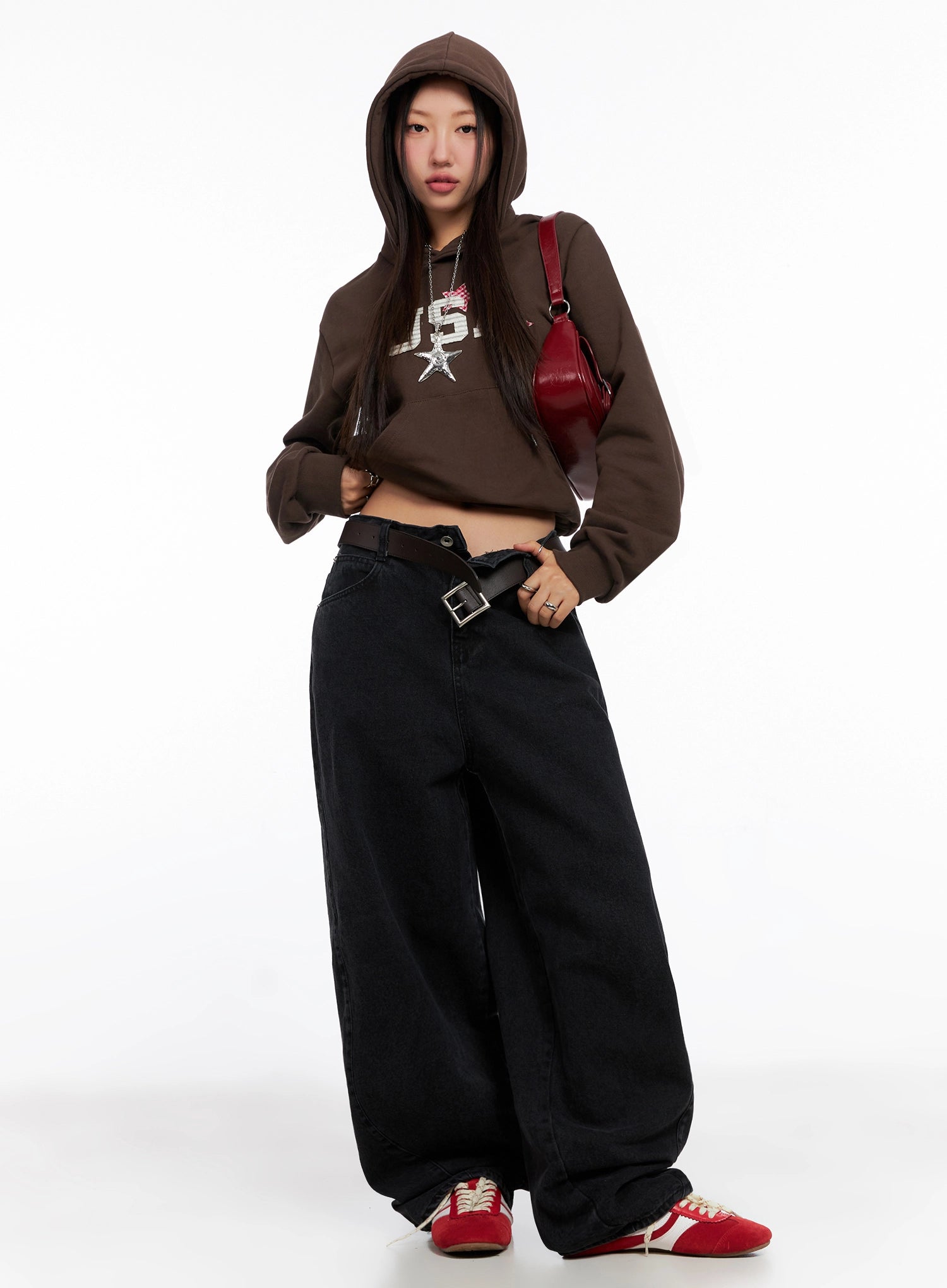 Sunwoo Embroidered Wide Leg Jeans IG528 in black, front full-body on model with hood up, loose fit wide-leg cotton denim belted at waist, styled with brown crop hoodie, red bag, and red sneakers.
