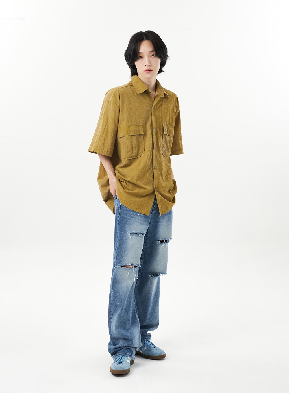Ripped Jeans Unisex CU315 in mid blue, full-body front on male model arms at sides, wide-leg destroyed denim with prominent thigh and knee rips, paint splatter detailing, tomboy unisex styling.