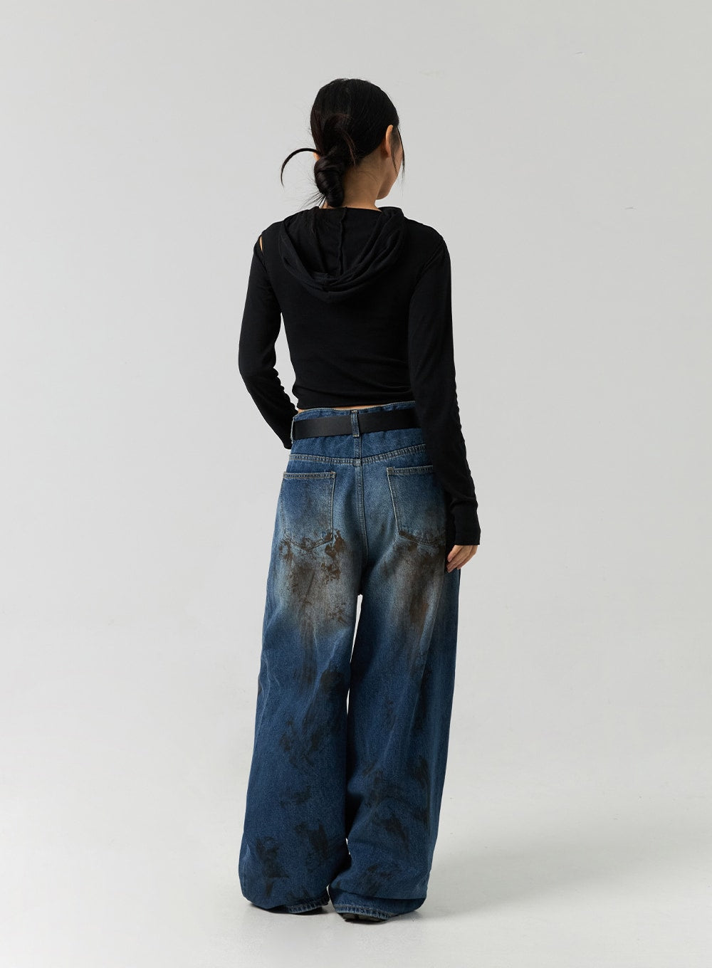 Street-Style Wide Fit Washed Jeans CO323 in Blue, full back view on model in black hooded crop top, wide leg cotton denim with back pockets and brown washed stain pattern pooling at hem.