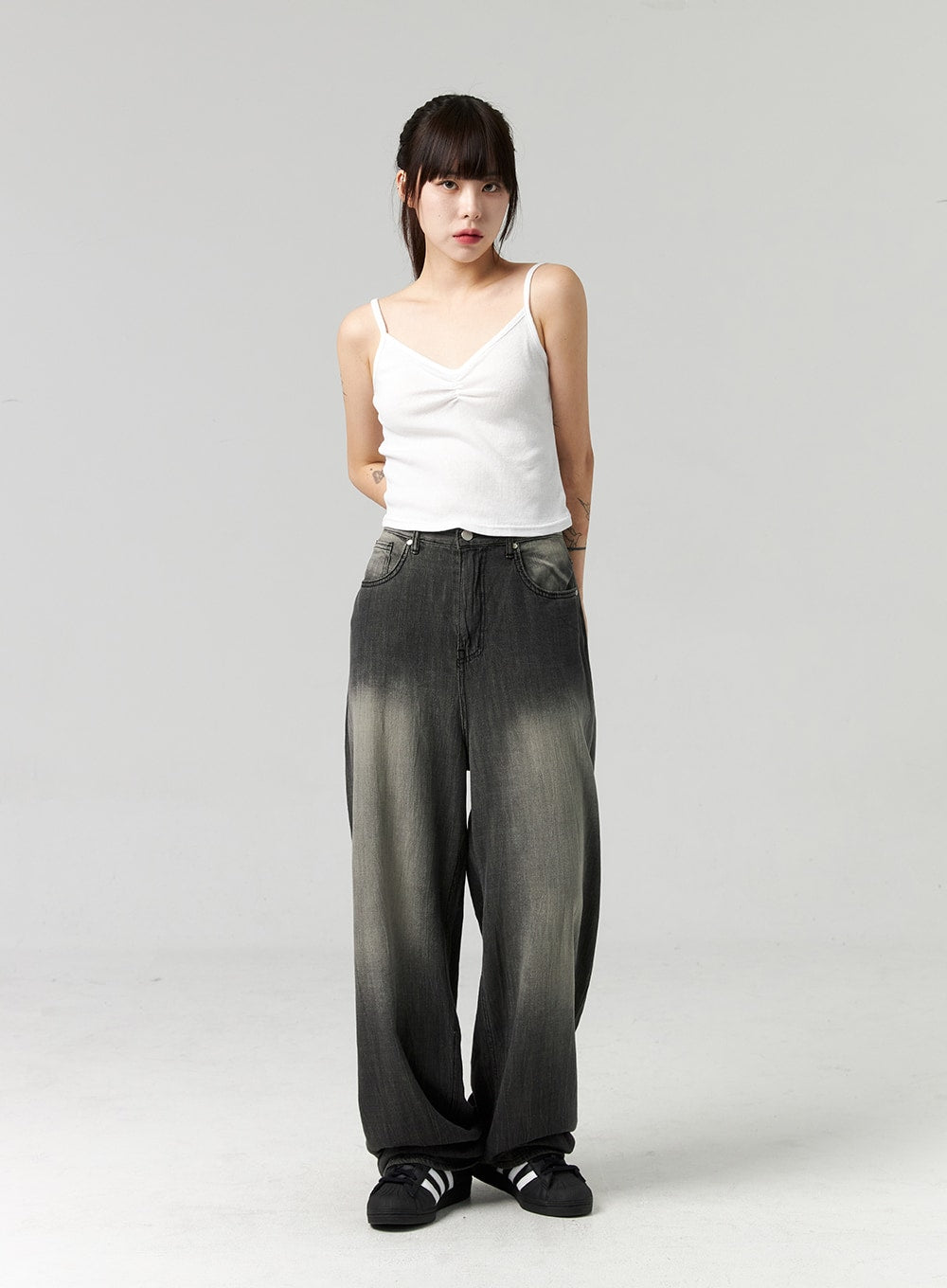Baggy Jeans CL321 in washed dark grey, full-body front view on model standing straight, wide-fit gradient washed denim, floor-grazing length, paired with white cami and black sneakers.