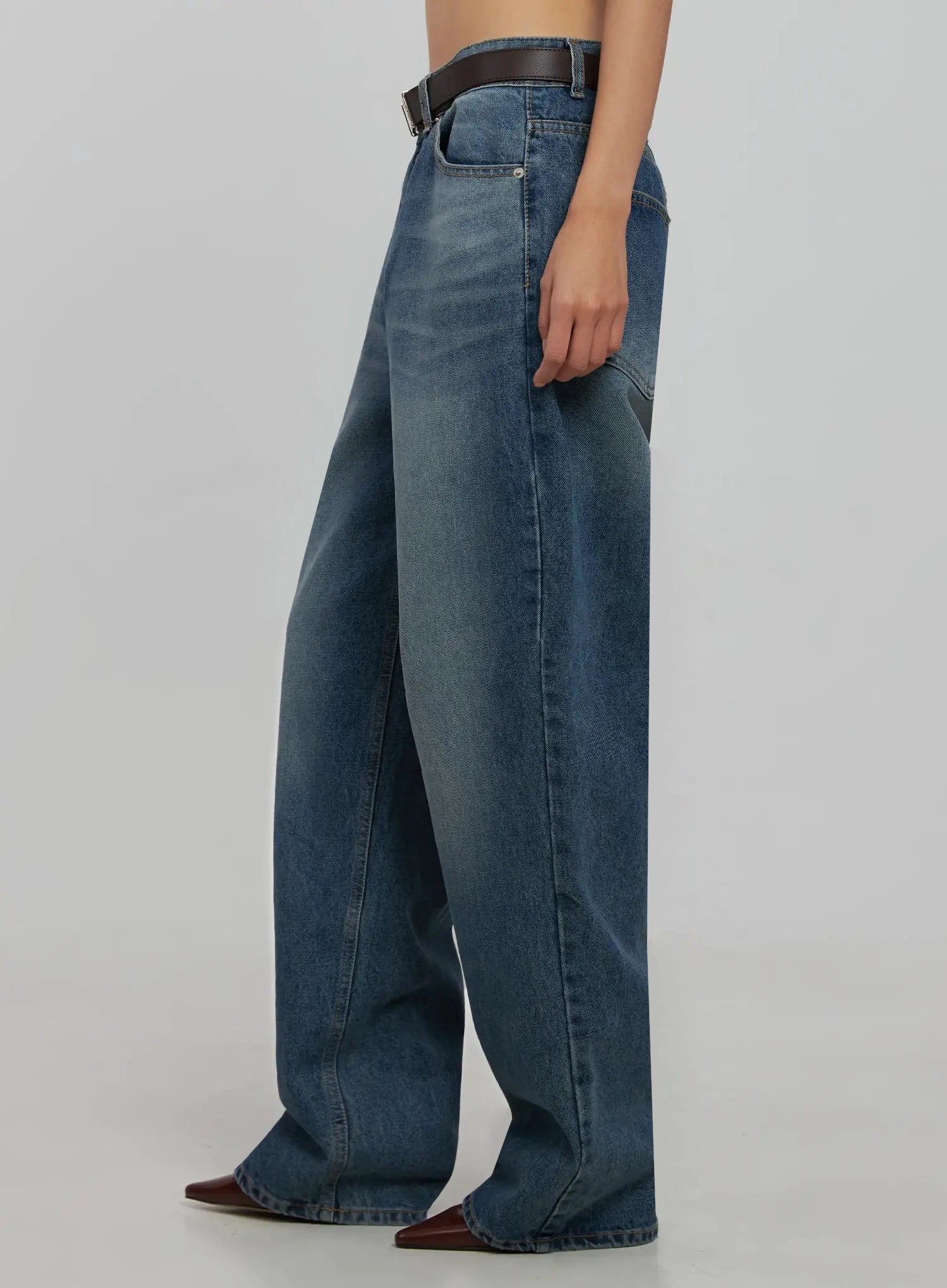 Akira Wide Leg Jeans IJ508 in blue, side close-up on model, highlighting washed fade, wide-leg drape, and side pocket detail with brown leather belt.