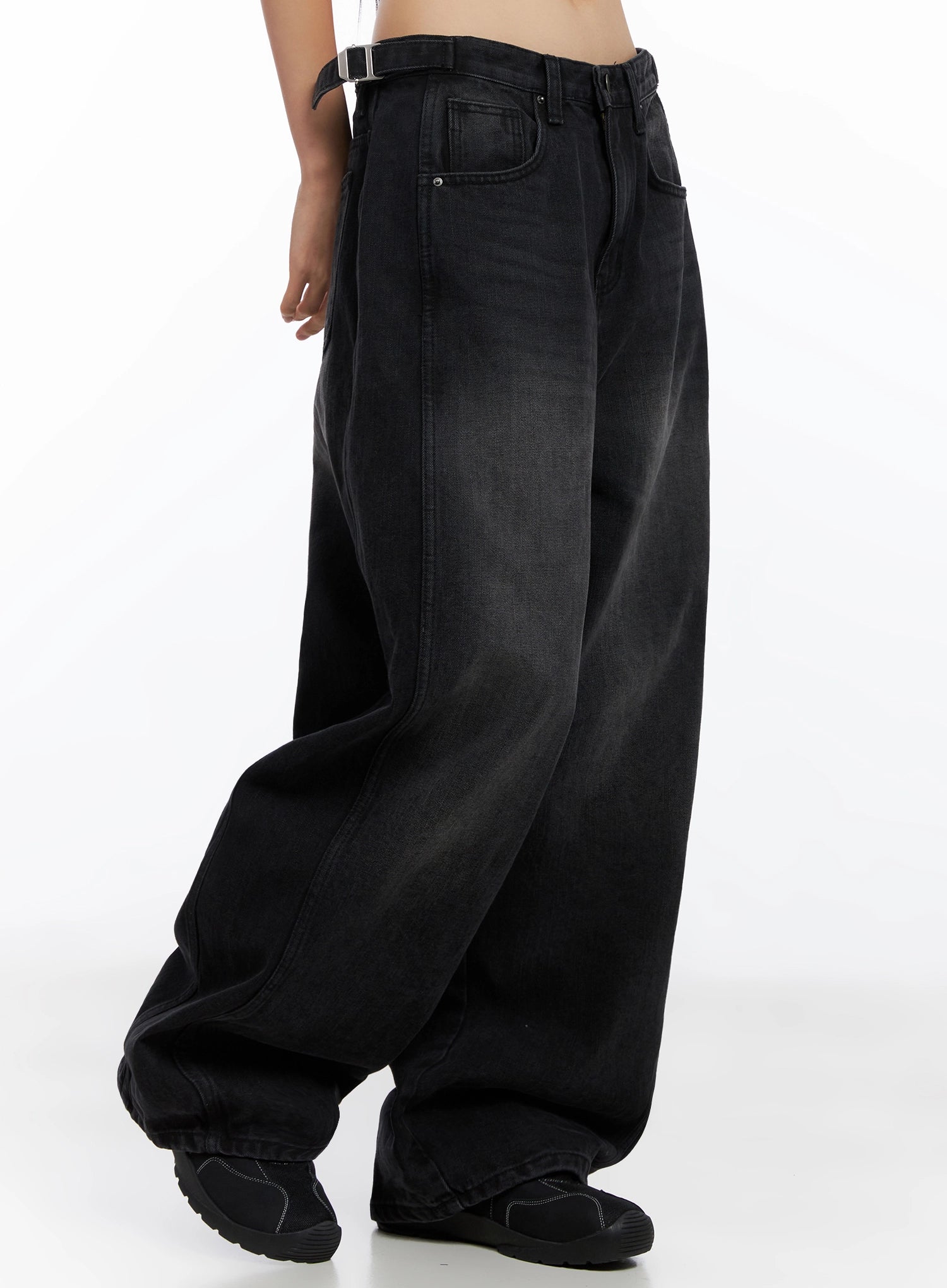 Goffel Side Belt Washed Wide Denim Pants IO517 in black, side lower-body shot on model, side belt buckle at waist, sweeping wide leg length pooling at hem over black sneakers.
