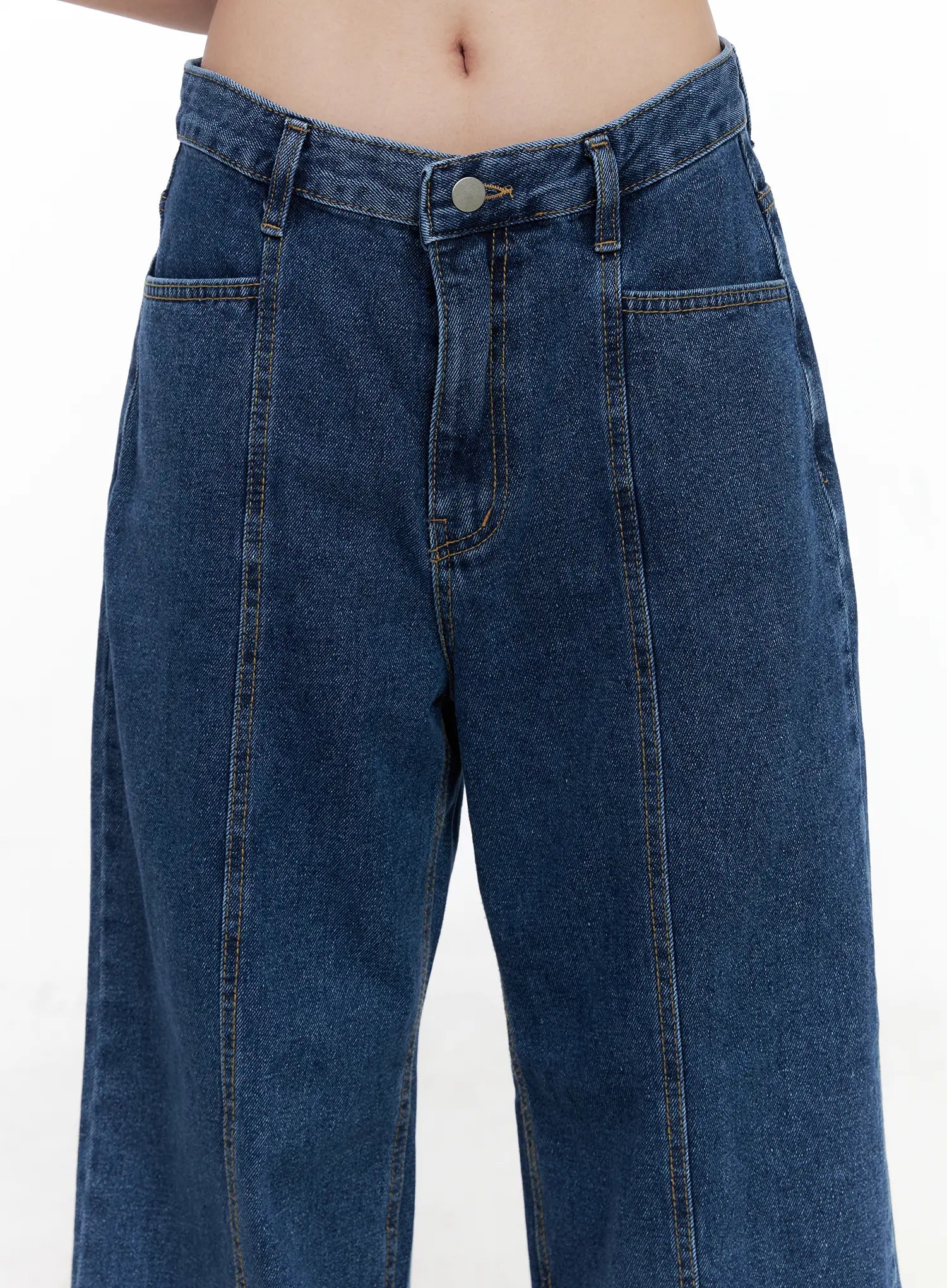 Eliza Seam Detail Relaxed Bootcut Jeans CO521 in washed blue, front waist close-up on model, raised seam panel stitching from waist down thigh, front pockets and button closure detail.