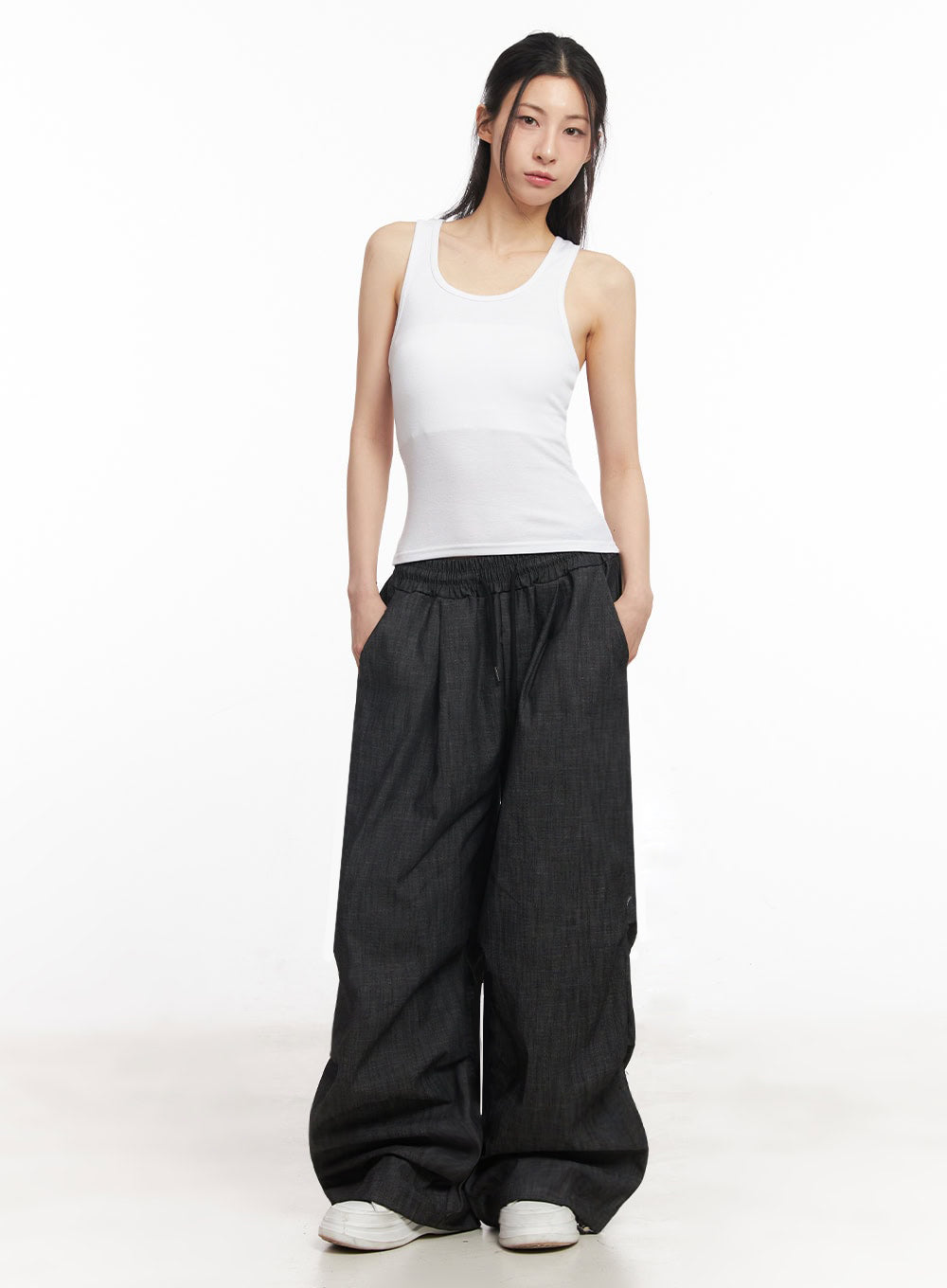 Pintuck Denim Sweatpants IY529 in black, full-body front view on model, baggy wide-fit cotton denim with banded elastic waist, paired with fitted white tank top and white sneakers.
