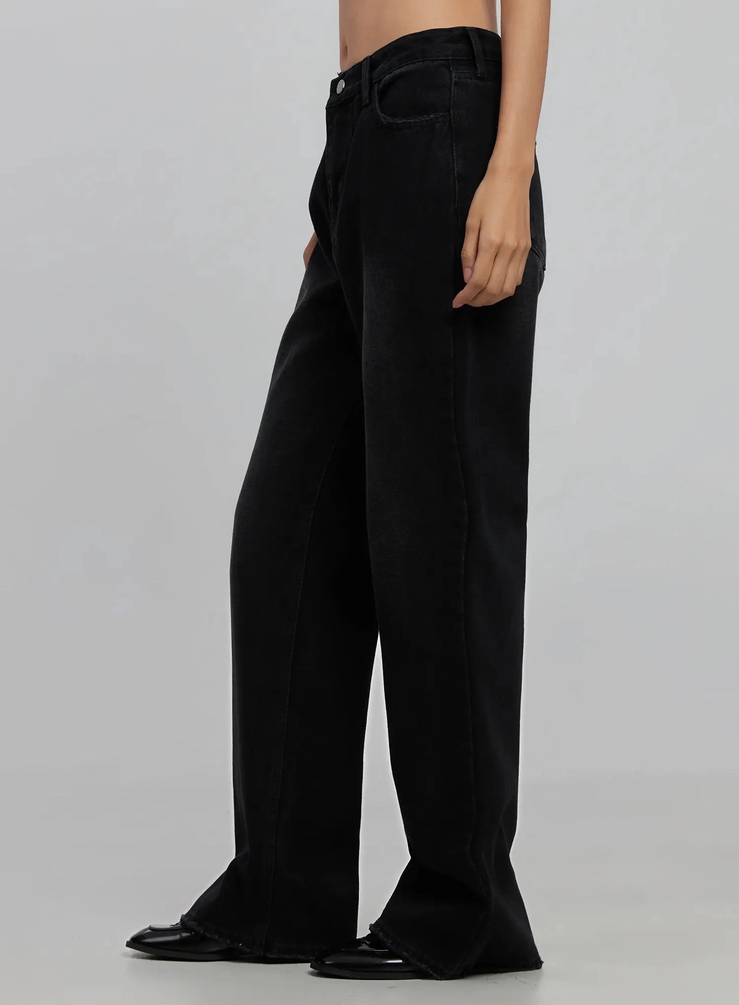 Imani Wide-Leg Flared Jeans ID516 in black, side product view on model (waist to toe), showing wide-leg flare silhouette and side seam, faded black cotton denim, black loafers at hem.