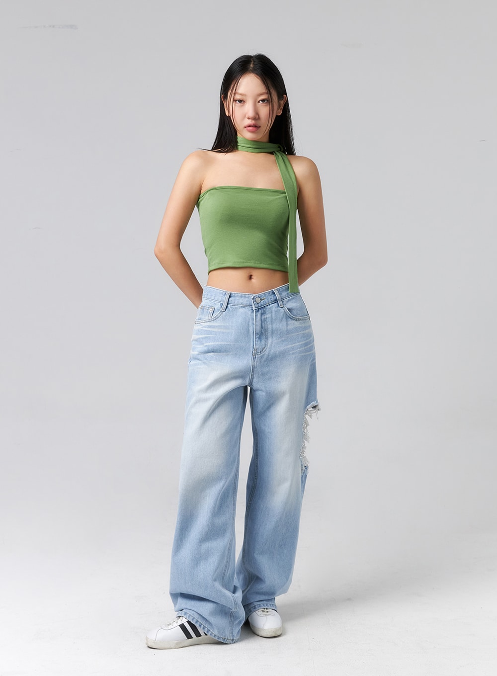 Ripped Side Jeans CL320 in light blue, full-length front shot on model hands behind back, wide-fit faded denim with side destroyed tear at thigh, styled with green halter top and Adidas sneakers.