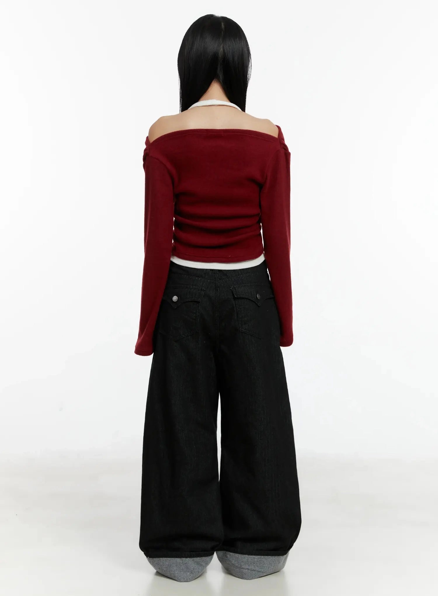 Amyra Baggy Striped Jeans ID525 in black, back view on model, showing rear flap pockets and wide baggy fit, grey cuffed hem, paired with red off-shoulder knit, full-length shot.