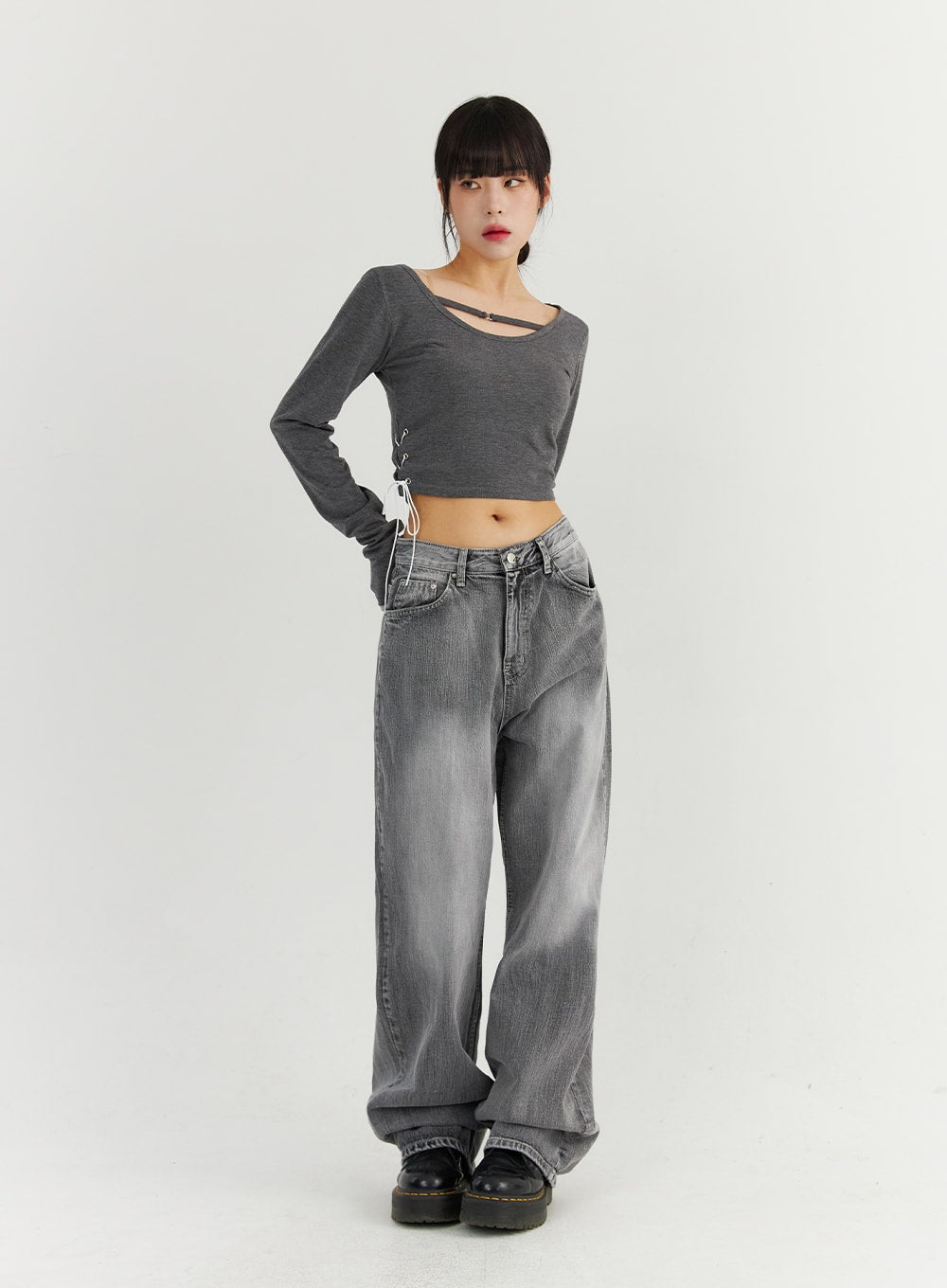 Grey Washed Wide Leg Jeans CO323 in Gray, full-body front view on model with hand on hip, relaxed low-rise wide-leg cotton denim with faded wash, styled with gray crop top and platform boots.