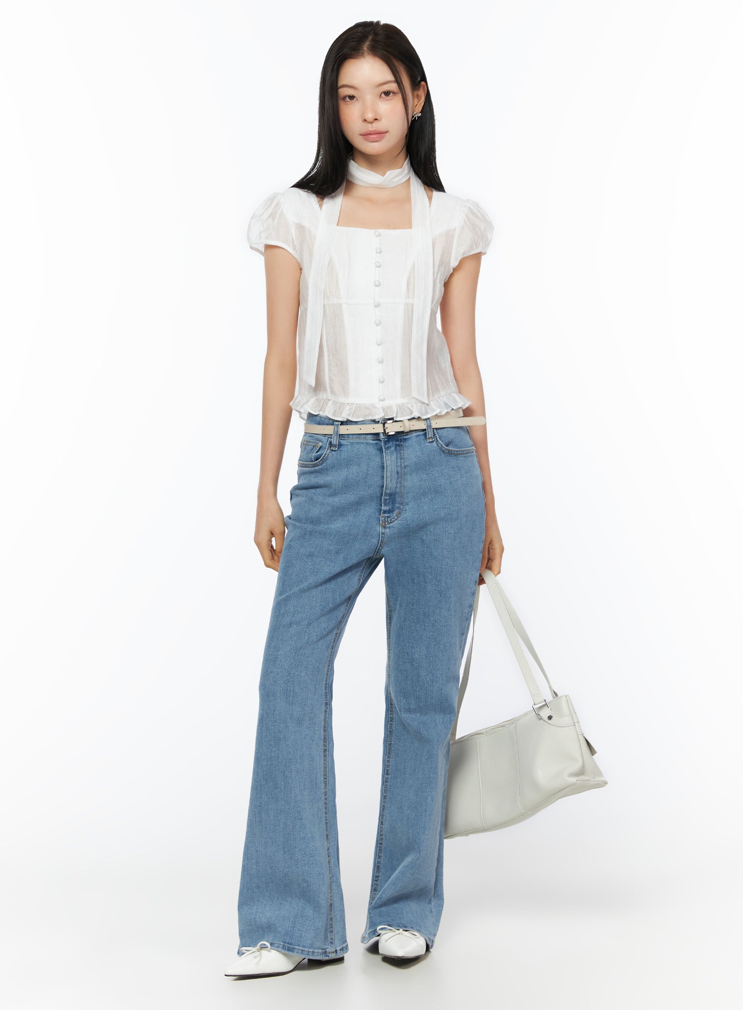 Puff Sleeve Shirred Blouse with Scarf IU519 in white, full-body front view on model holding white bag, puff sleeves, button-front, ruffled hem, scarf at neck, paired with flare jeans and belt.