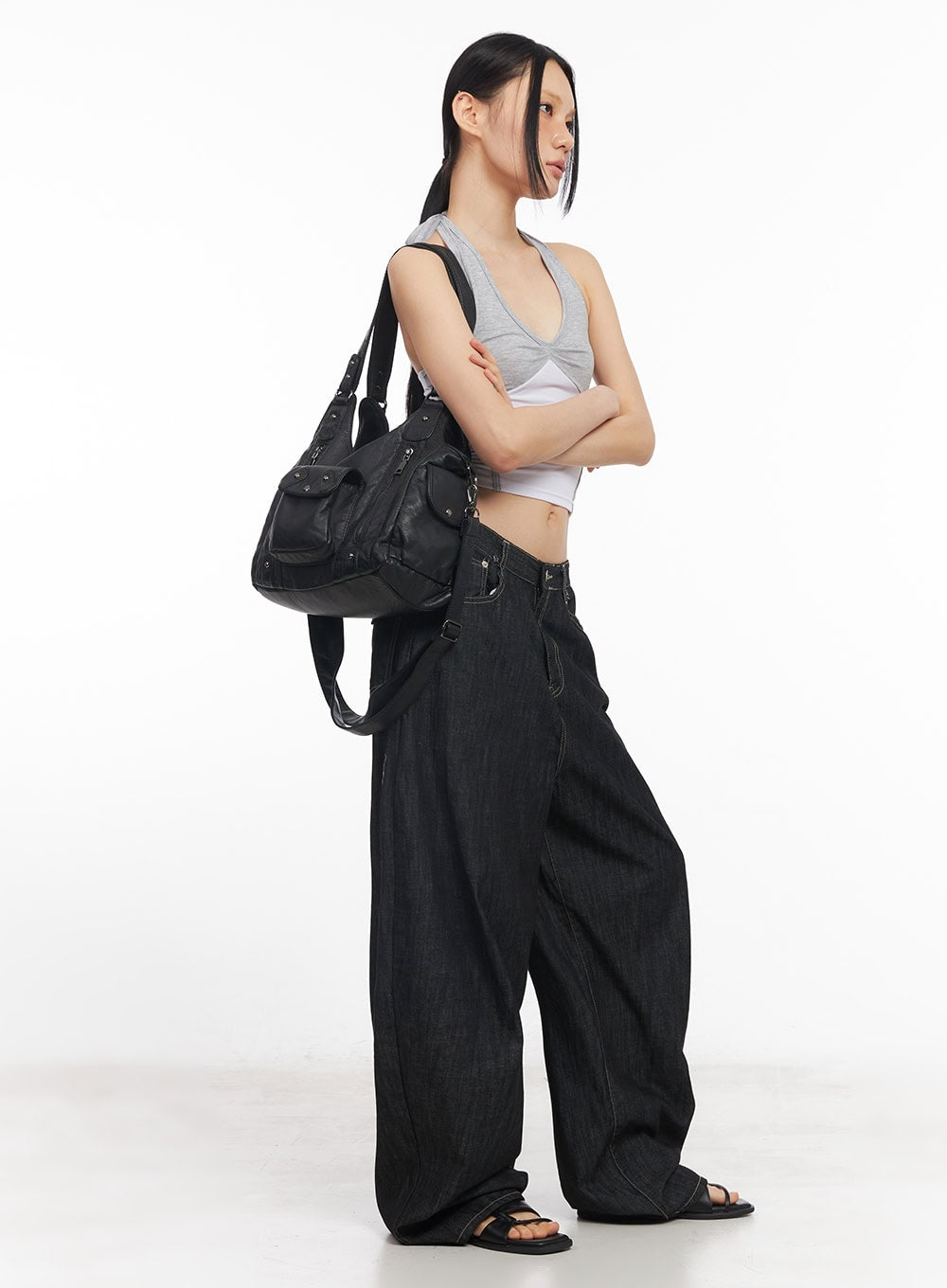 Elvie Baggy Jeans CY528 in black, side full-length editorial shot on model, voluminous wide-leg denim with arms crossed, paired with crop top and oversized leather bag.
