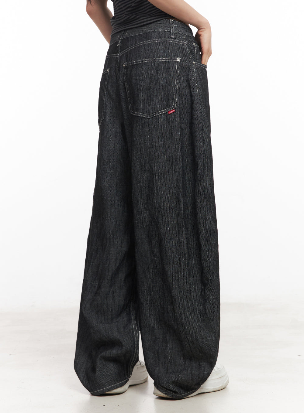 Lilli Wide-Leg Baggy Jeans IY516 in Black, back close-up on model, back pocket detail with red woven label and contrast stitching, sweeping wide-leg hem, white sneakers.