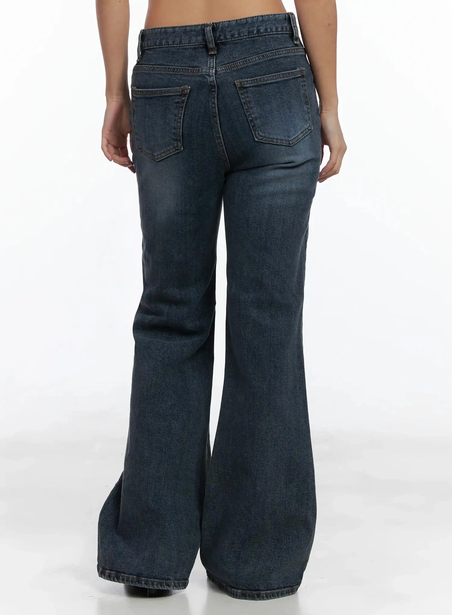 Rara Fleece Flared Jeans ID503 in blue, back full-body view on model, washed denim with dual rear patch pockets and dramatic flared hem, waistband with belt loop detail visible.