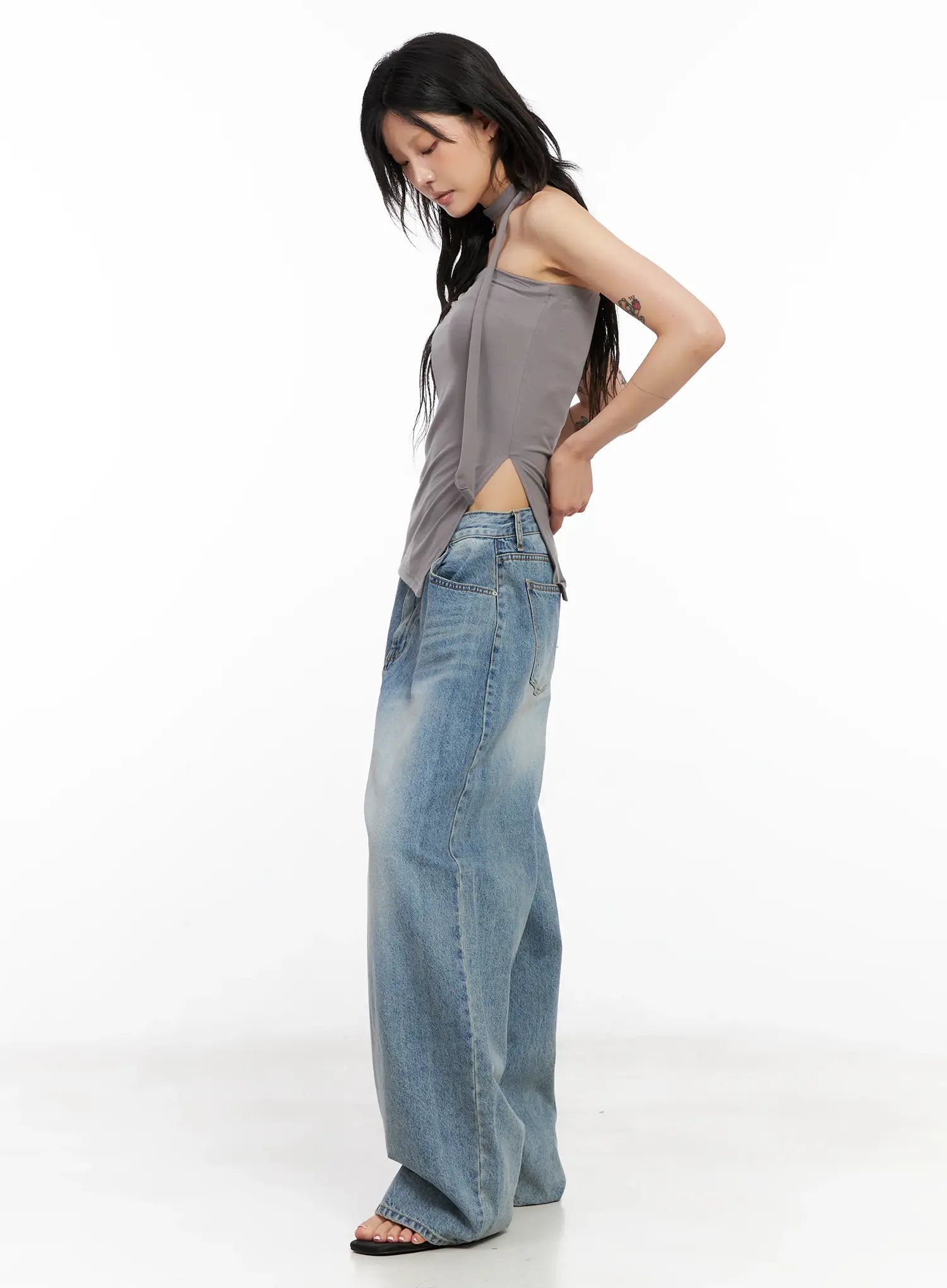 Koko Vintage-Wash Baggy Jeans CL528 in blue, side full-length on model looking down, wide-leg faded denim paired with grey halter top and black sandals.