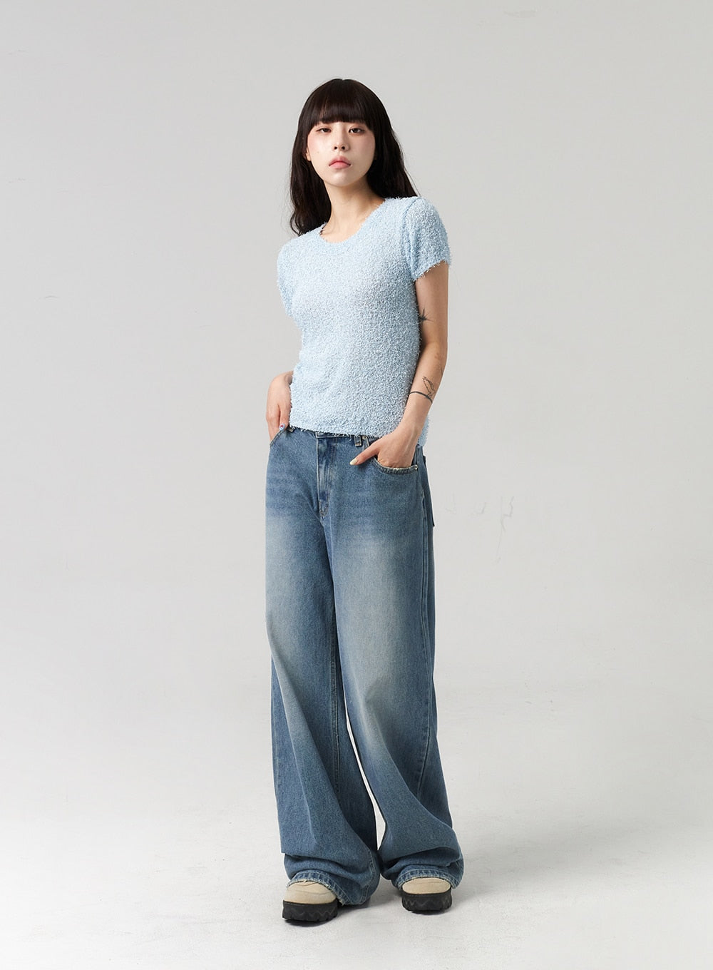 Baggy Jeans CL313 in washed blue, full-length front view on model with hands in pockets, wide-leg washed denim with gradient fade, paired with light blue bouclé short-sleeve top.