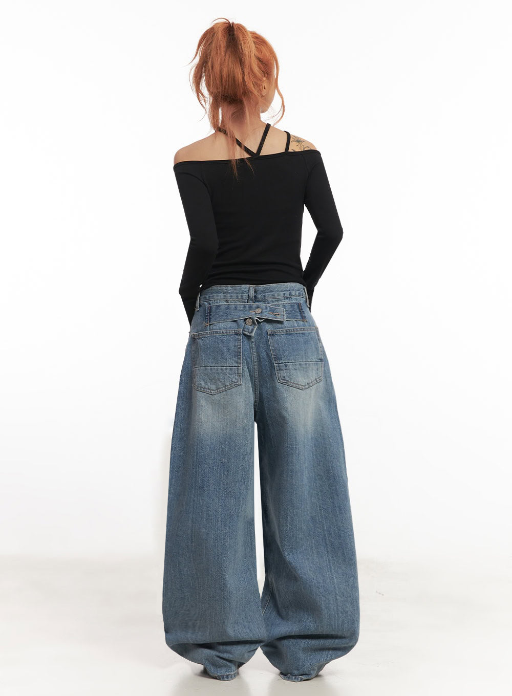 Yvette Washed Baggy Jeans IA517 in light blue, back full-body view on model, wide baggy leg with patch pockets and crossover waistband, washed denim, styled with black off-shoulder long-sleeve top.