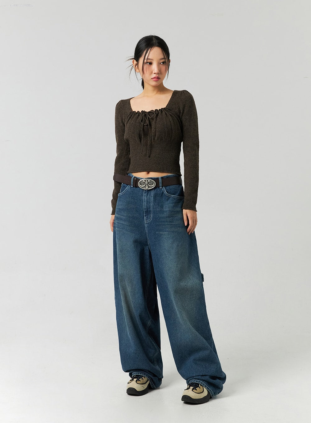 Washed Cotton Wide Leg Jeans CO323 in blue, full-body slight side-front on model, washed wide leg cotton denim with high-rise fit and side carpenter pocket, styled with brown knit crop and sneakers.
