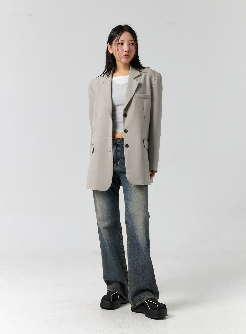 Vintage Wash Bootcut Jeans CS305 in blue, full-body slight side front on model looking away, vintage wash fading visible, normal fit bootcut leg, paired with beige blazer.