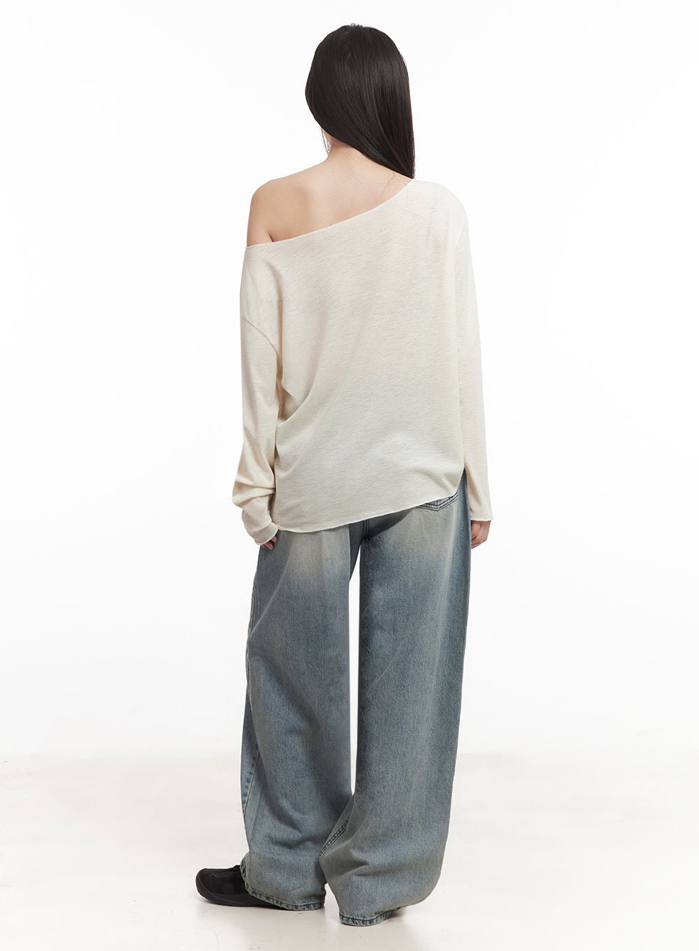Casey Washed Baggy Jeans IM528 in light blue, back full-length on model, wide-fit washed denim with gradient fade, voluminous leg silhouette, paired with cream off-shoulder knit top and black shoes.
