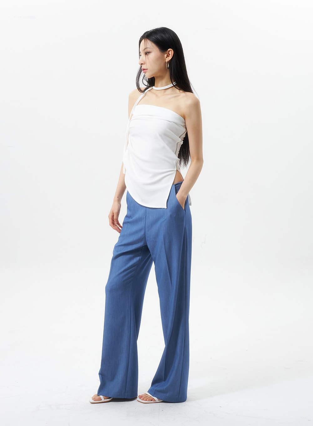 Low Rise Tailored Pants IU326 in blue, three-quarter front view on model looking to side, low-rise wide-leg trouser with pressed crease, hand in pocket, styled with white halter choker top.
