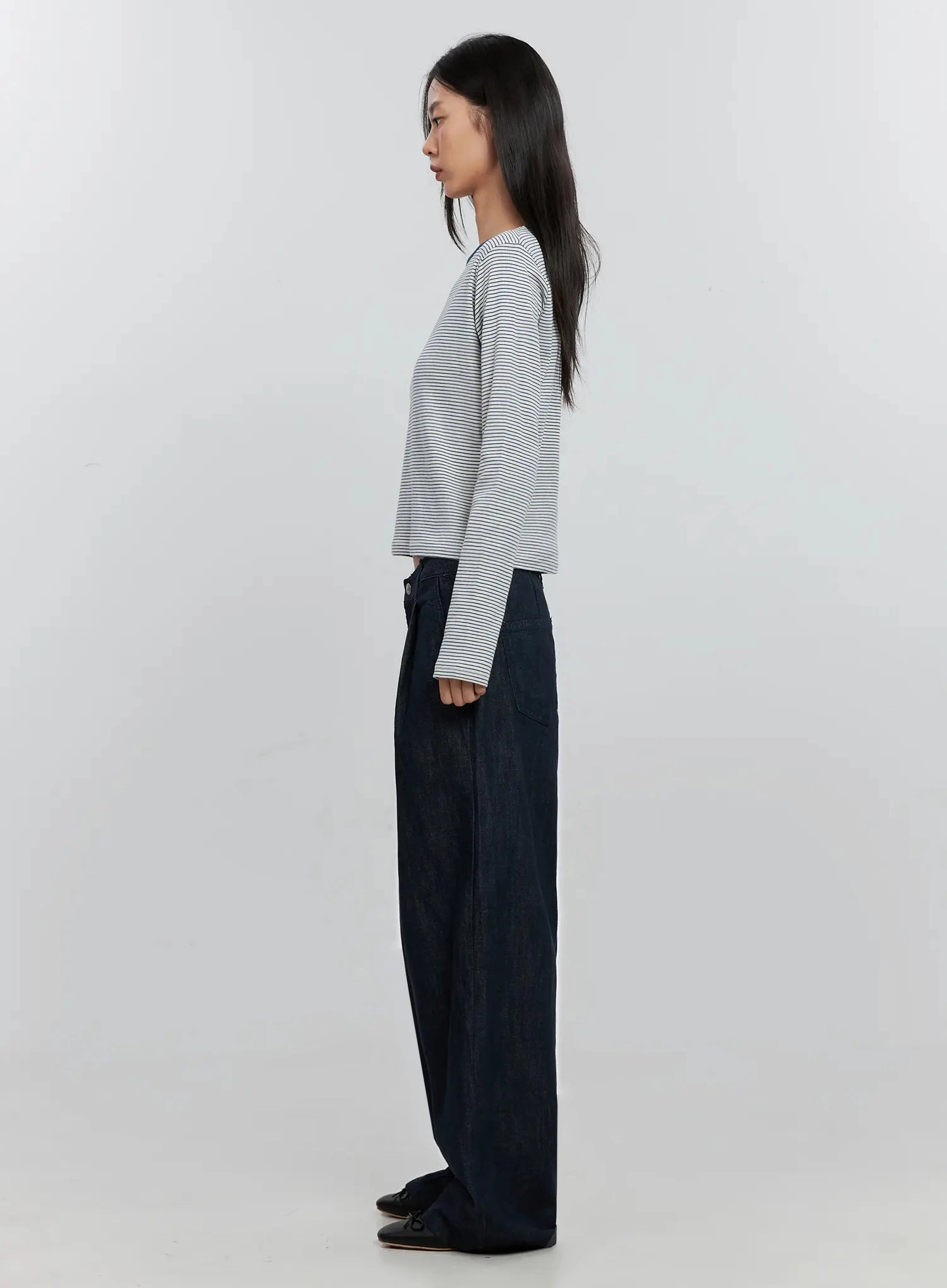 Elio Pintuck Wide-Leg Jeans IS516 in dark indigo, side full-length on model, floor-length wide leg with pintuck pleats, paired with striped crop top and black loafers.