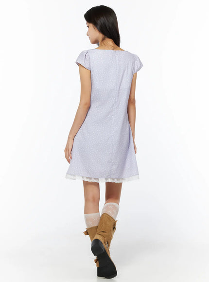 Romantic Floral Lace Trim Mini Dress CU522 in light purple, back three-quarter view on model walking, flutter cap sleeves, flared A-line skirt, cream lace trim at hem, tan boots and lace socks.