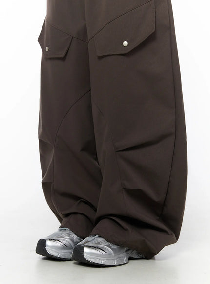 Wide Leg Pintuck Cargo Pants CU519 in dark brown, lower-leg close-up on model, oversized wide leg with curved pintuck seams, gathered hem bunching at ankle over silver sneakers.
