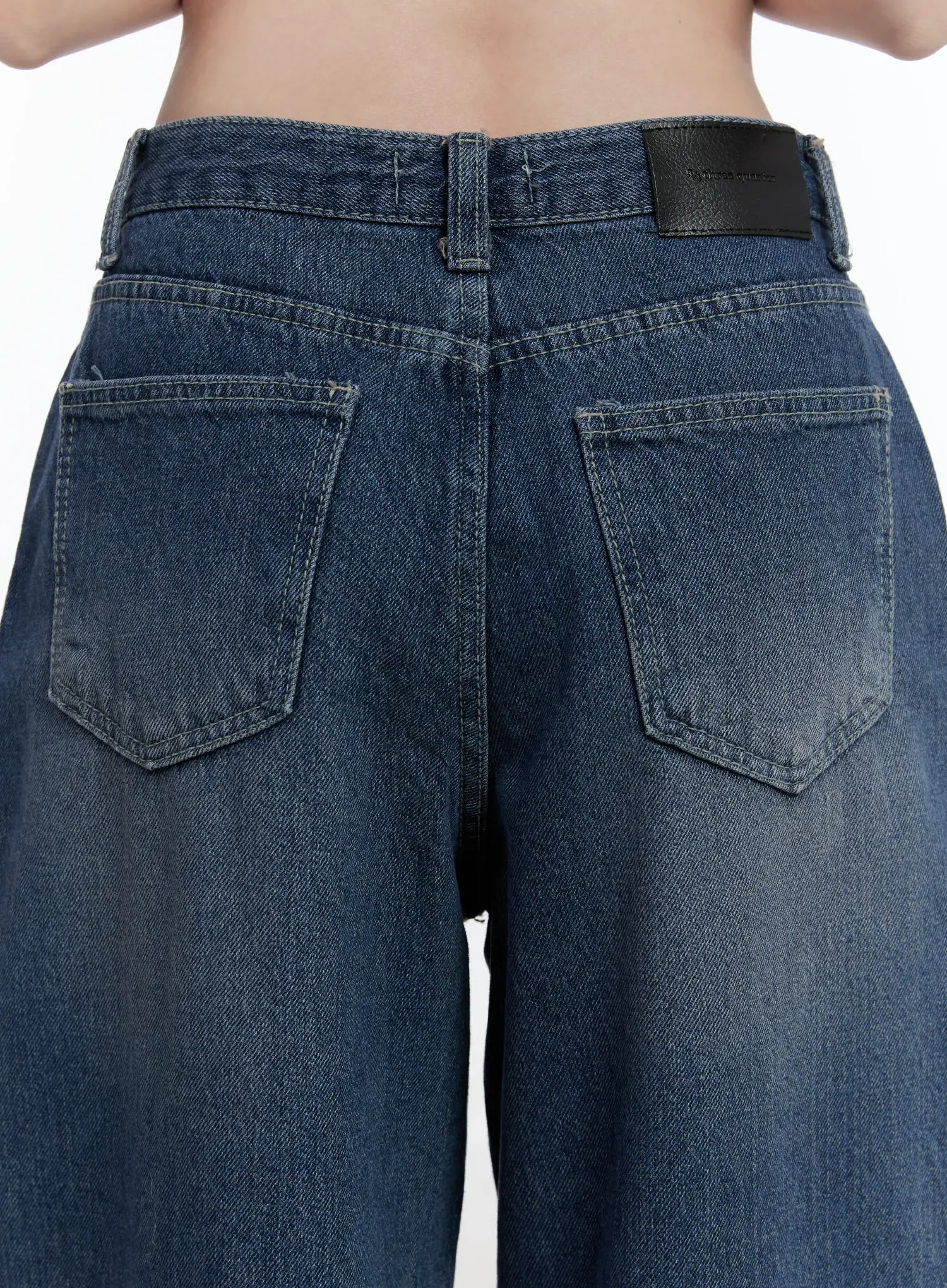 Della Casual Denim Wide Jeans ID511 in blue, close-up back waist detail shot on model, dual back pockets and leather logo patch at waistband, washed cotton texture visible.