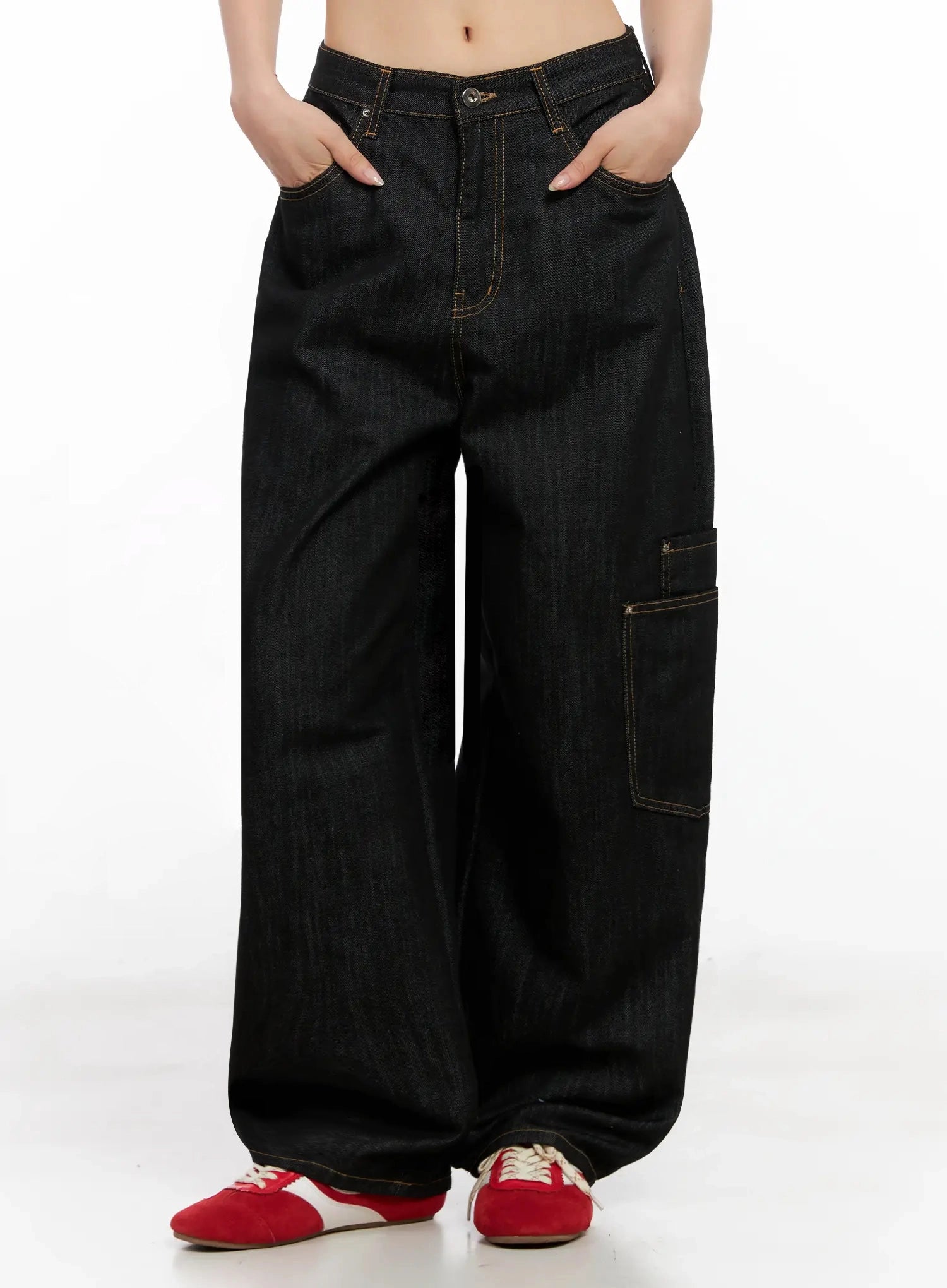 Dahee Wide-Leg Cargo Jeans IG508 in black, front mid-shot on headless model hands in pockets, lower cargo pocket detail on right leg, contrast topstitching on wide-fit cotton denim, paired with red sneakers.