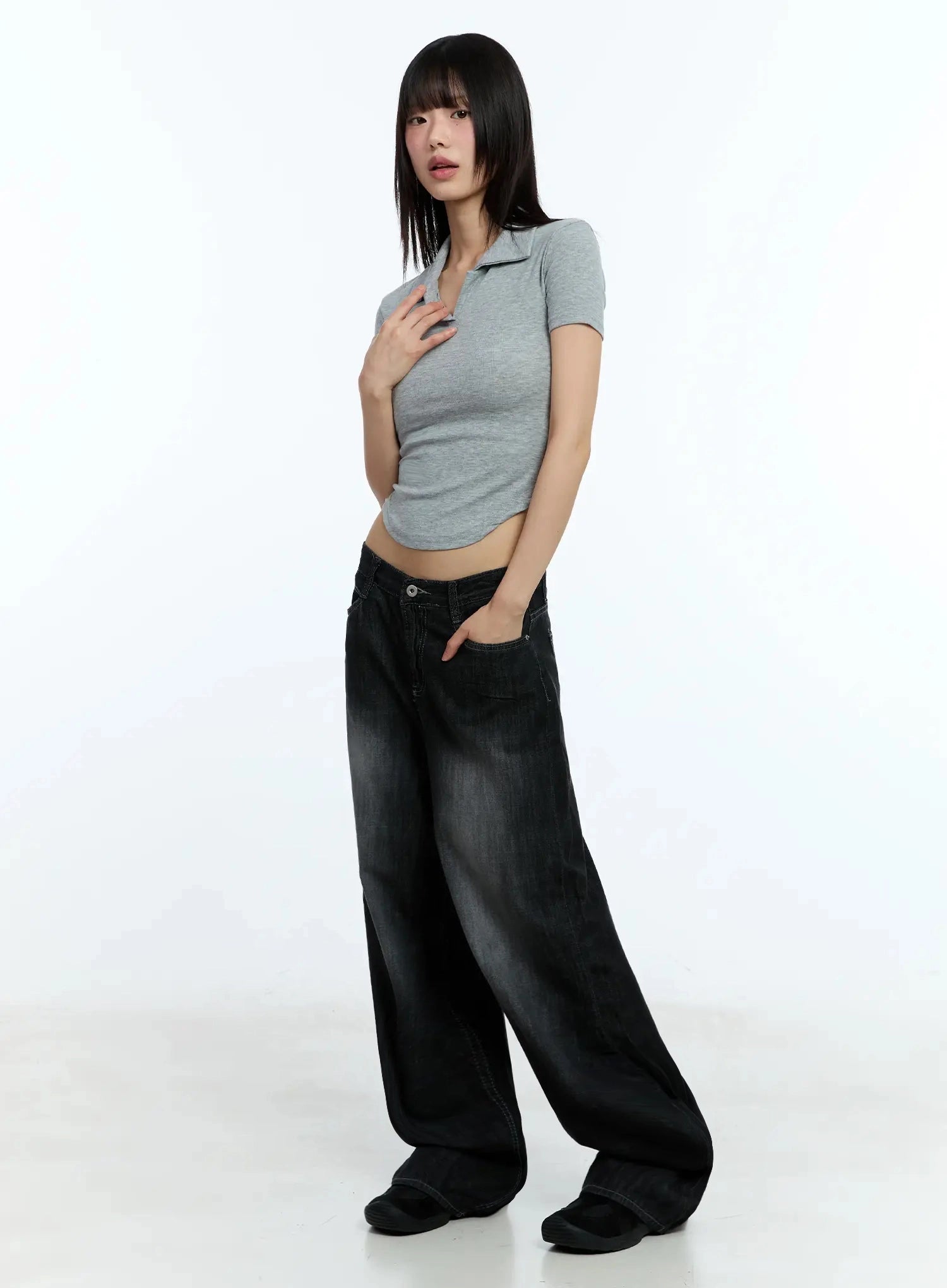 Wendy Washed Wide-Leg Jeans IU524 in black, three-quarter side shot on model with hand in pocket, washed denim wide-leg silhouette, styled with grey polo crop top, low-rise waist visible.
