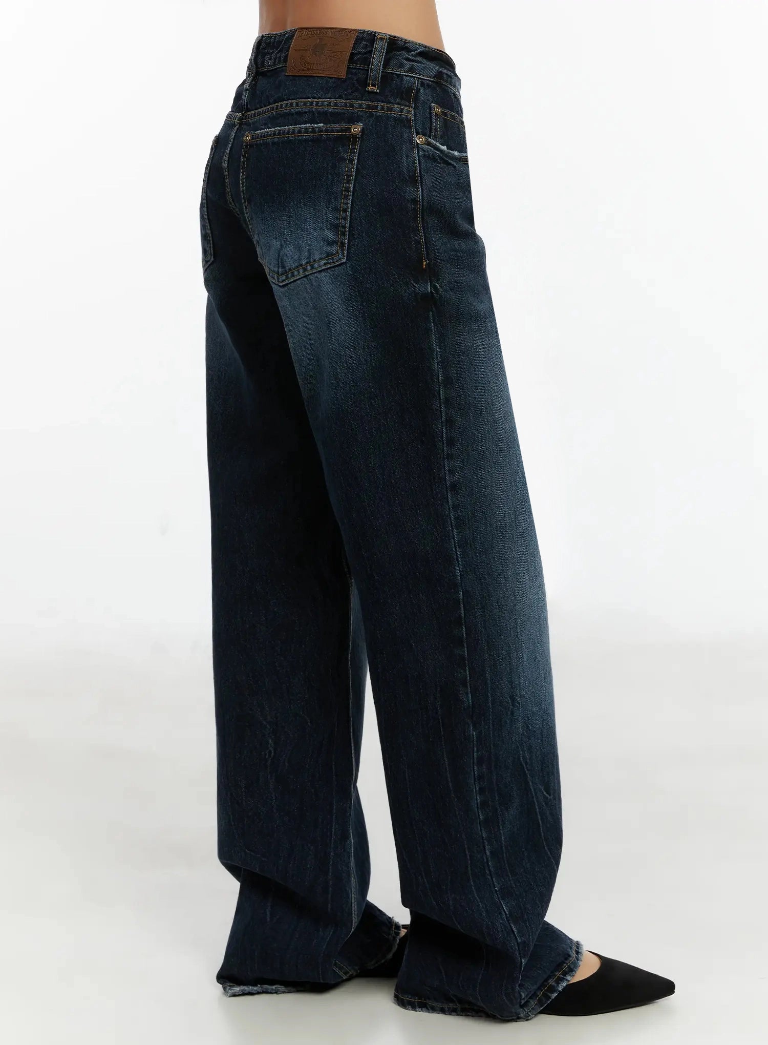Aimee Low Rise Wide Leg Jeans ID525 in dark blue wash, side-back close-up on model from waist down, back pocket with rivet, leather patch at waistband, washed cotton wide leg.