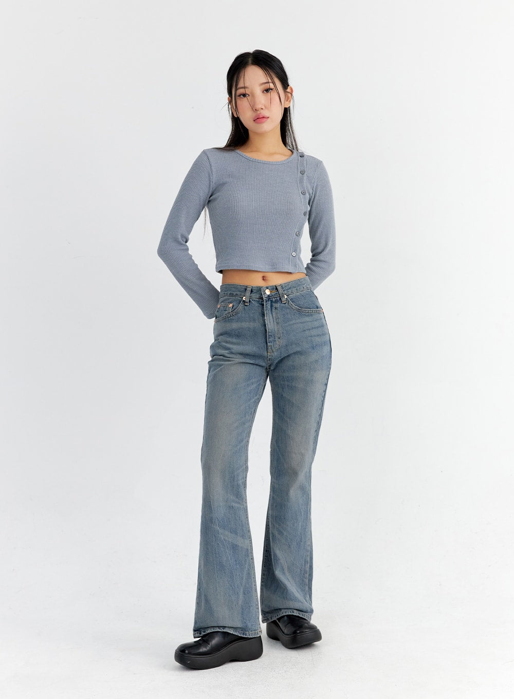 Vintage Washed Bootcut Jeans CO325 in blue, full-body front shot on model with hand behind back, slim fit washed denim with bootcut flare, paired with blue-grey ribbed crop top and black loafers.