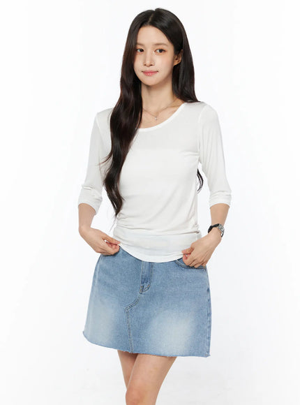 Sheer Three-Quarter Sleeve Top CU522 in white, front smiling pose on model, soft sheer fabric with round neck and slim fit, hands resting at waist, worn with blue denim mini skirt.