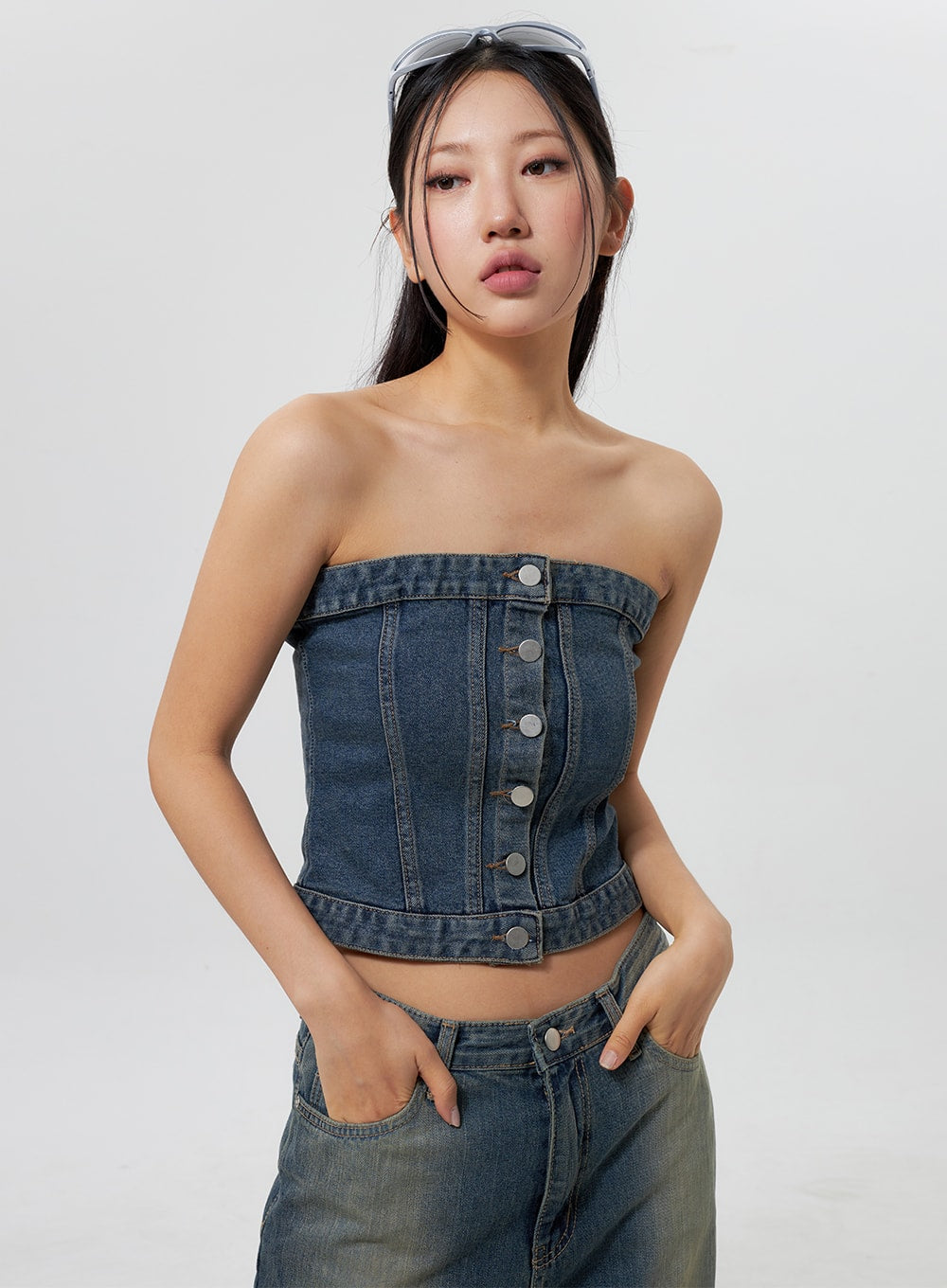 Low Rise Wide Leg Jeans CY323 in vintage blue, upper-body close-up on model showing low-rise waistband and front pocket, hands in pockets, paired with denim bandeau crop top with silver buttons.