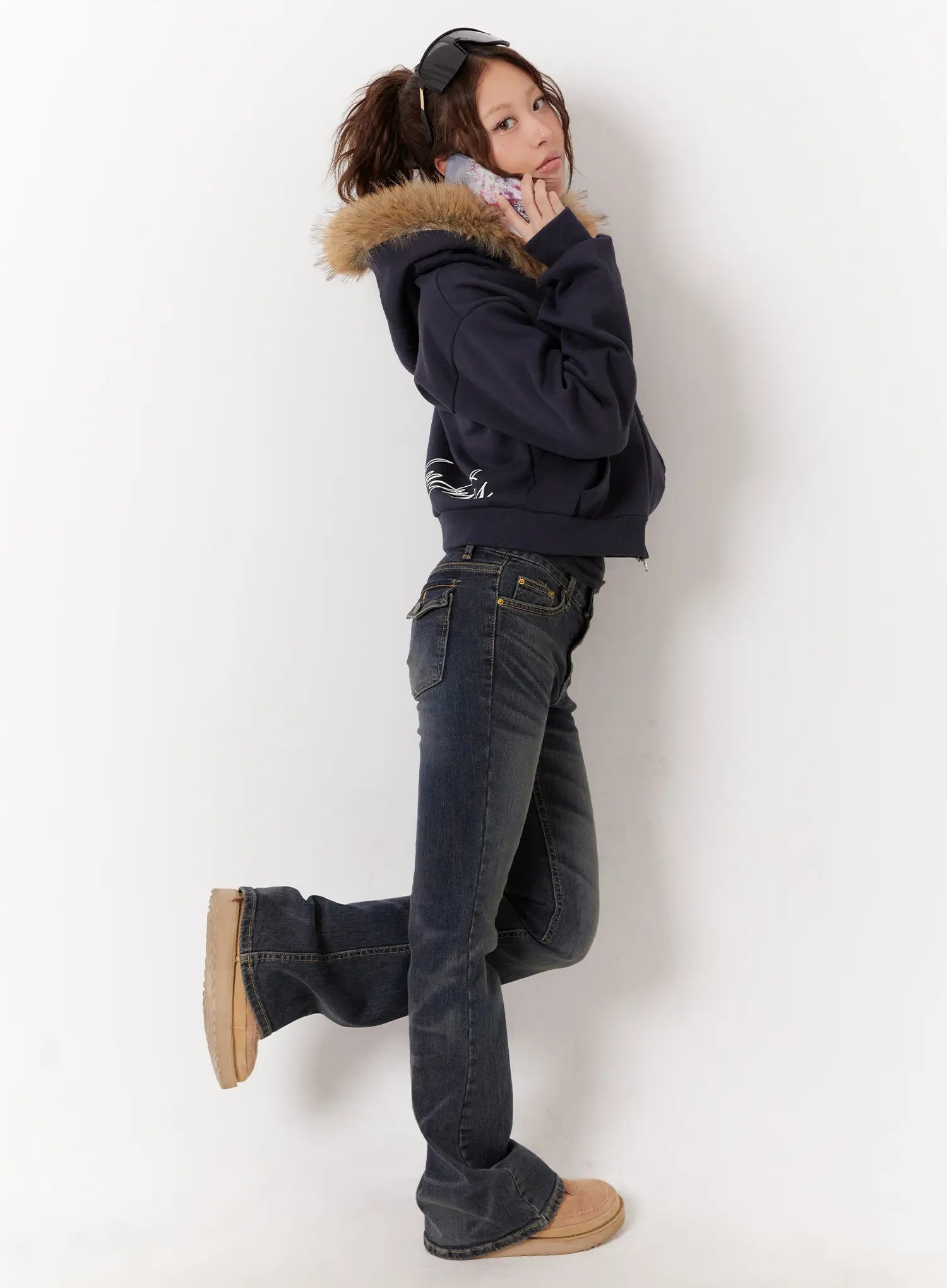 Kai Vintage Washed Flare Jeans CD515 in dark indigo, side profile on model with one leg raised, bootcut flare silhouette, low-rise fit, paired with navy hoodie and UGG boots.