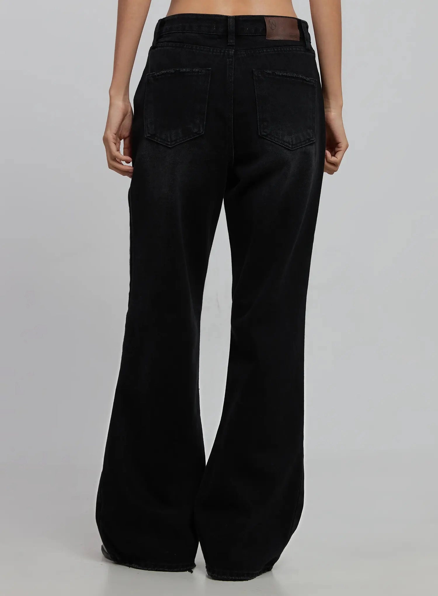 Imani Wide-Leg Flared Jeans ID516 in black, back product view on model (waist to hem), two back pockets with topstitching, leather label at waistband, flared hem, faded solid black cotton denim.