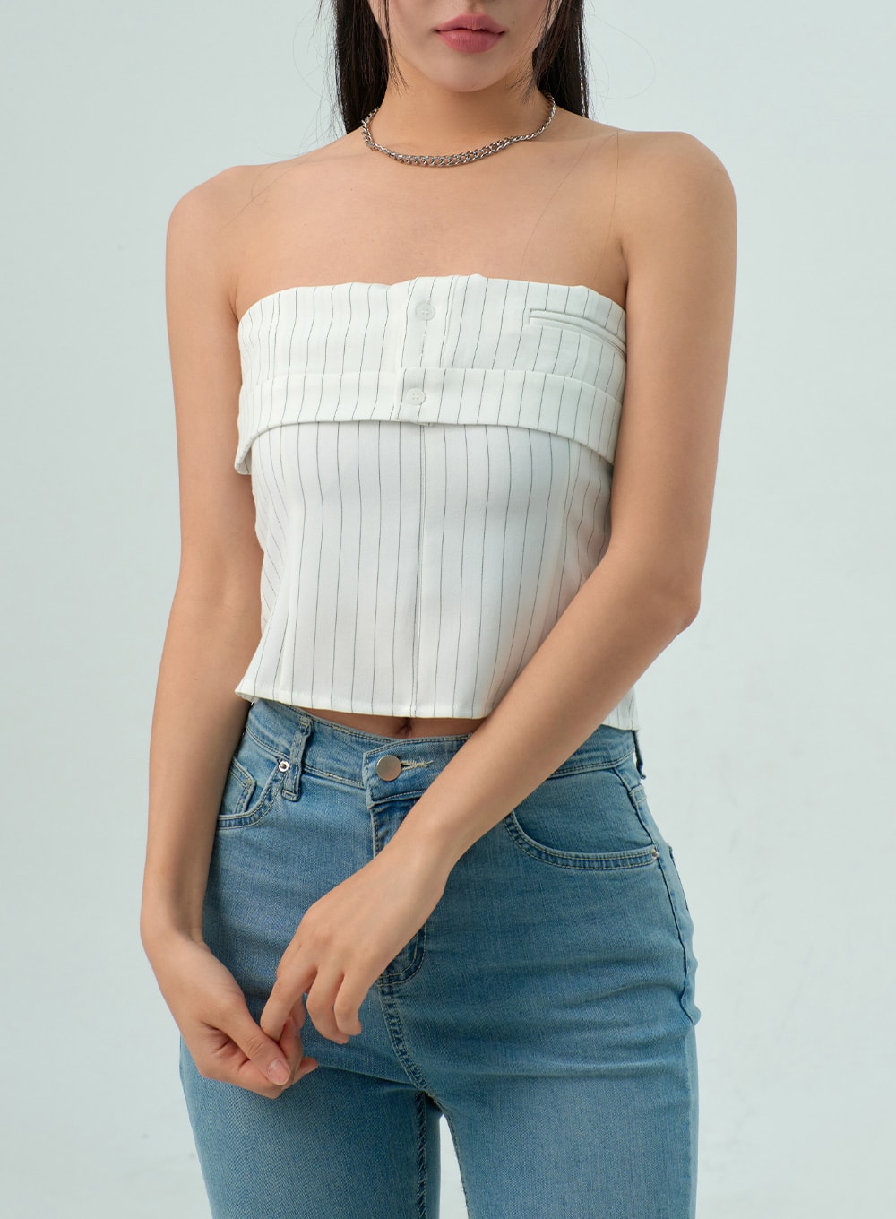 Light Wash Bootcut Jeans CY330 in light blue, upper waist close-up on model, high-rise button closure and front pocket detail visible, washed denim fabric, styled with white pinstripe tube top.