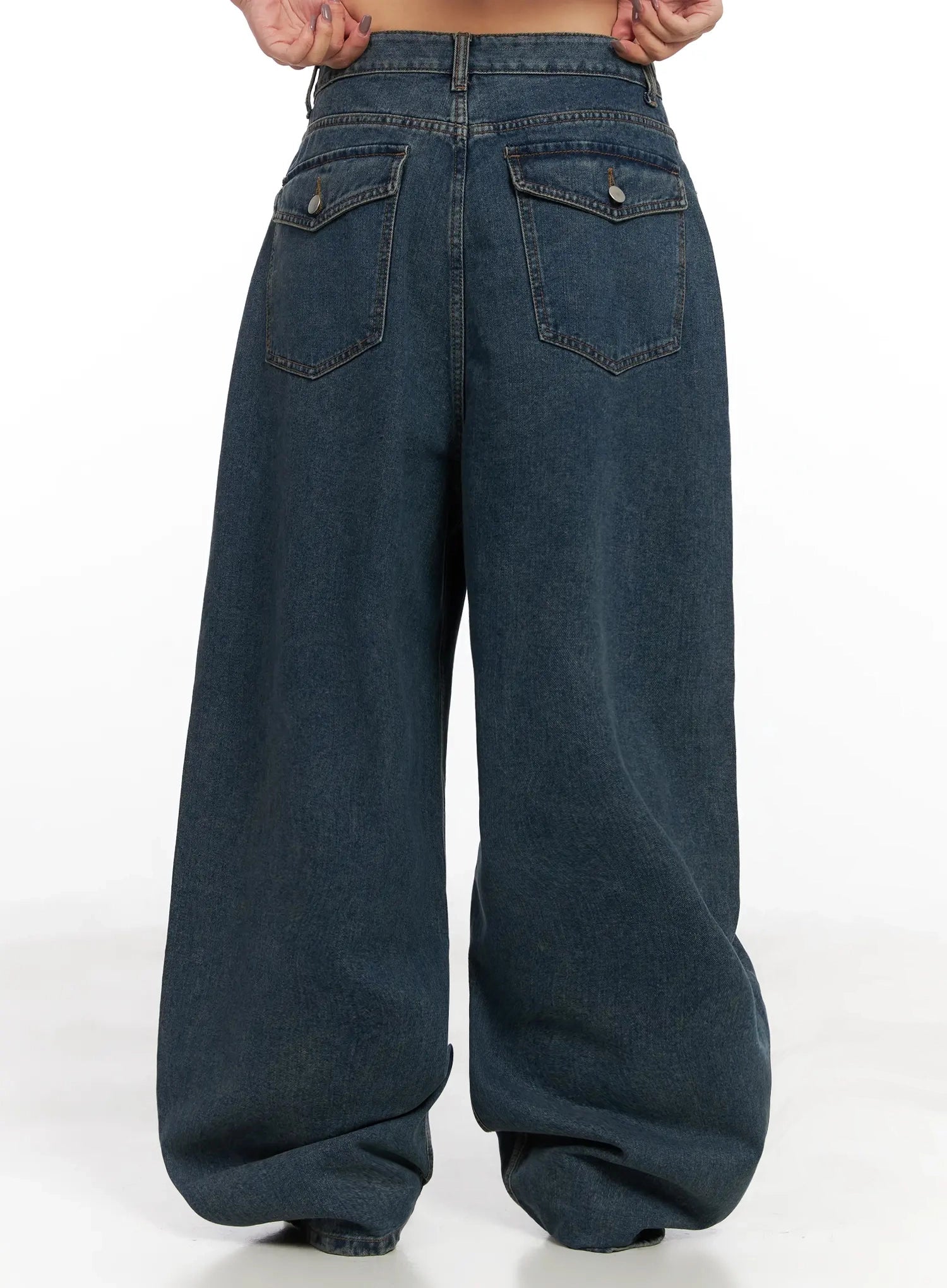 Aleena Mid-Wash Baggy Jeans IN528 in dark blue, back mid-shot on model, both hands on waistband, clearly showing back pocket placement and extreme wide-leg volume pooling at hem.
