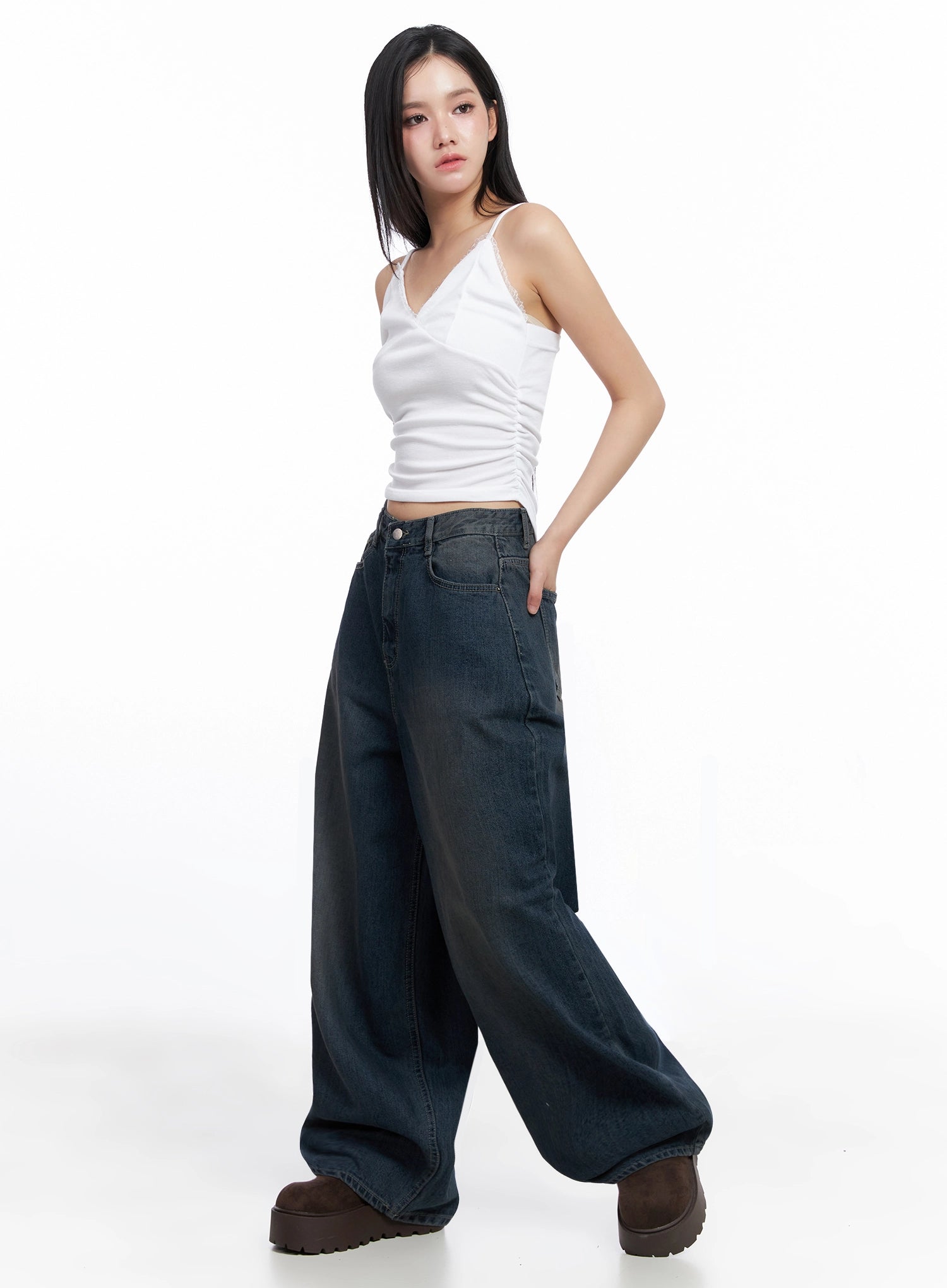 Adelyn Washed Baggy Jeans IS525 in dark blue, side full-body shot on model hand in pocket, wide baggy leg denim with washed finish, paired with white cropped cami and brown platforms.