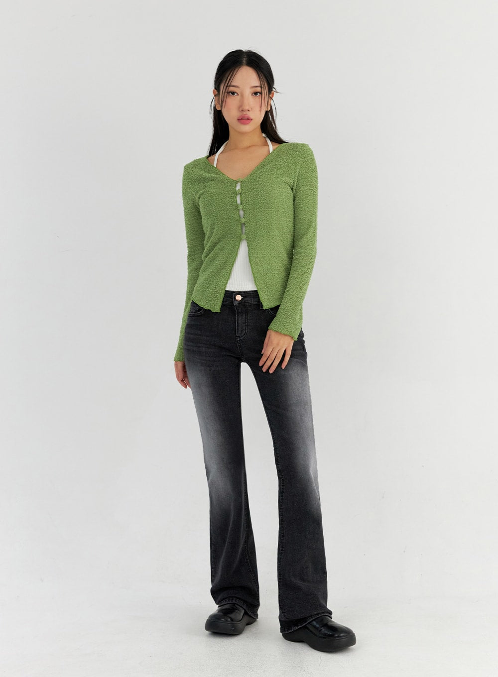 Bootcut Washed Jeans CO325 in dark gray, full-body front view on model, slim bootcut washed denim, darker wash tone visible, styled with green bouclé cardigan and white halter top underneath.