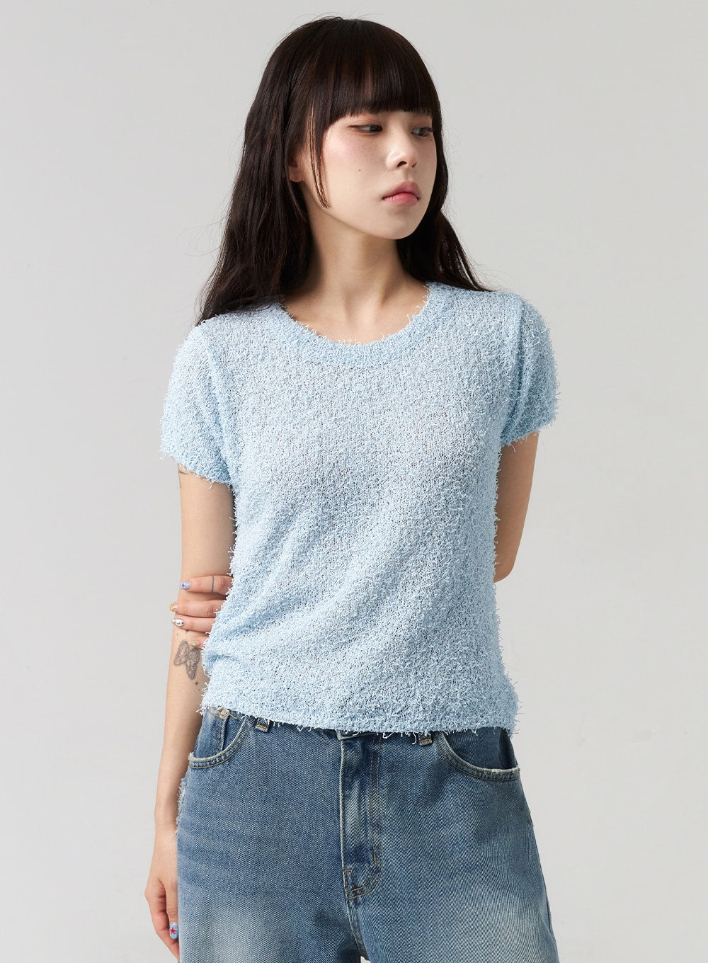 Baggy Jeans CL313 in washed blue, upper-body and waistband close-up on model, showing waistband, front pocket opening, and washed blue denim, styled with bouclé top.