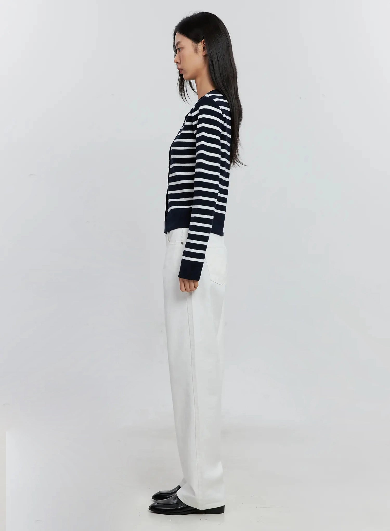 Taytum Straight-Leg Jeans IS515 in white, side view on model, straight-leg long cotton denim showing full leg silhouette, paired with navy striped cardigan and black loafers.