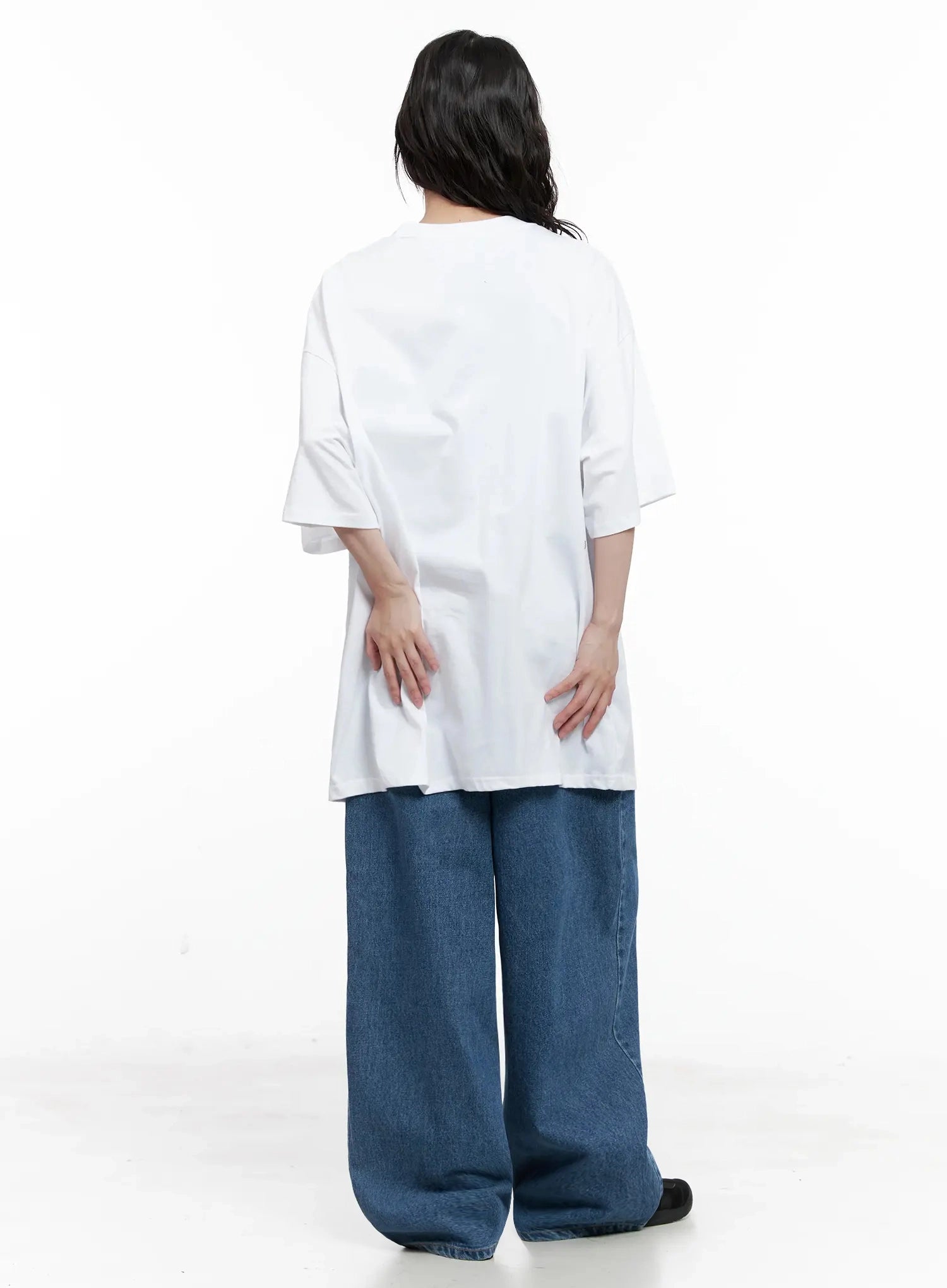 Pharita Loose-Fit Jeans IL528 in mid blue, back full-length view on model, wide-leg cotton denim showing voluminous leg silhouette, paired with white oversized graphic tee.
