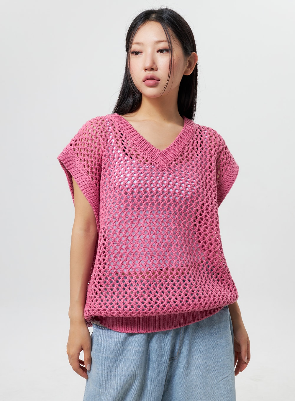 Oversized Ripped Jeans CY324 in light blue, upper waist close-up on model, wide-leg denim waistband partially visible beneath pink open-knit vest, casual layered look.