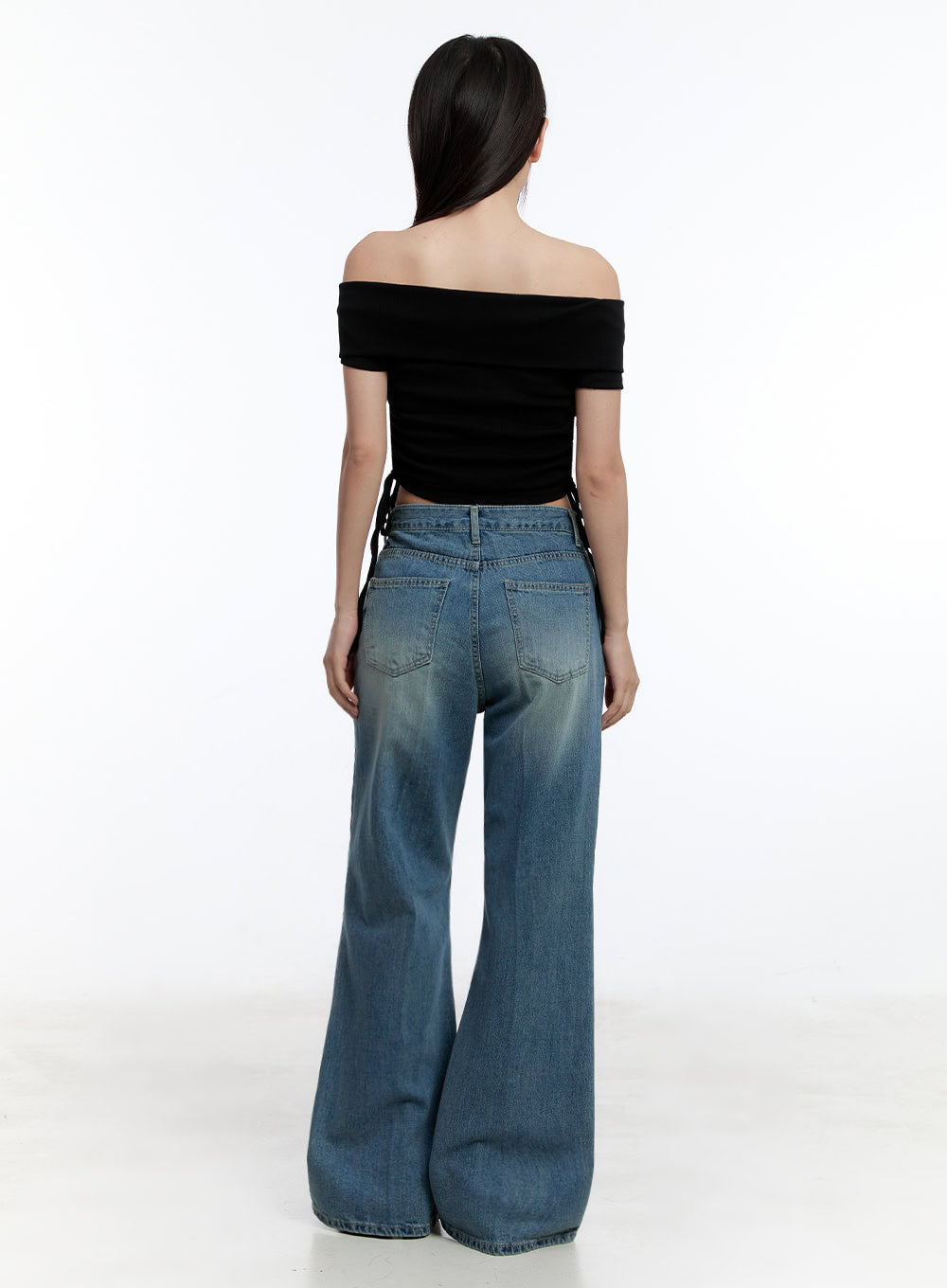 Aliya Washed Bootcut Jeans IU503 in dark blue, back full-body shot on model, showing two back pockets with washed fading, wide bootcut hem, paired with black off-shoulder crop top.