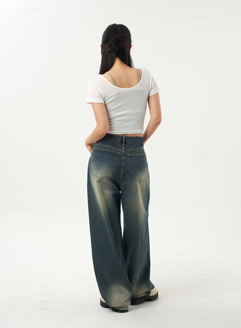 Mid-Rise Baggy Jeans CA325 in vintage blue denim, full-length back view on model, back pockets with stitching detail, sun-faded wide-leg denim pooling at heel, paired with white crop top.