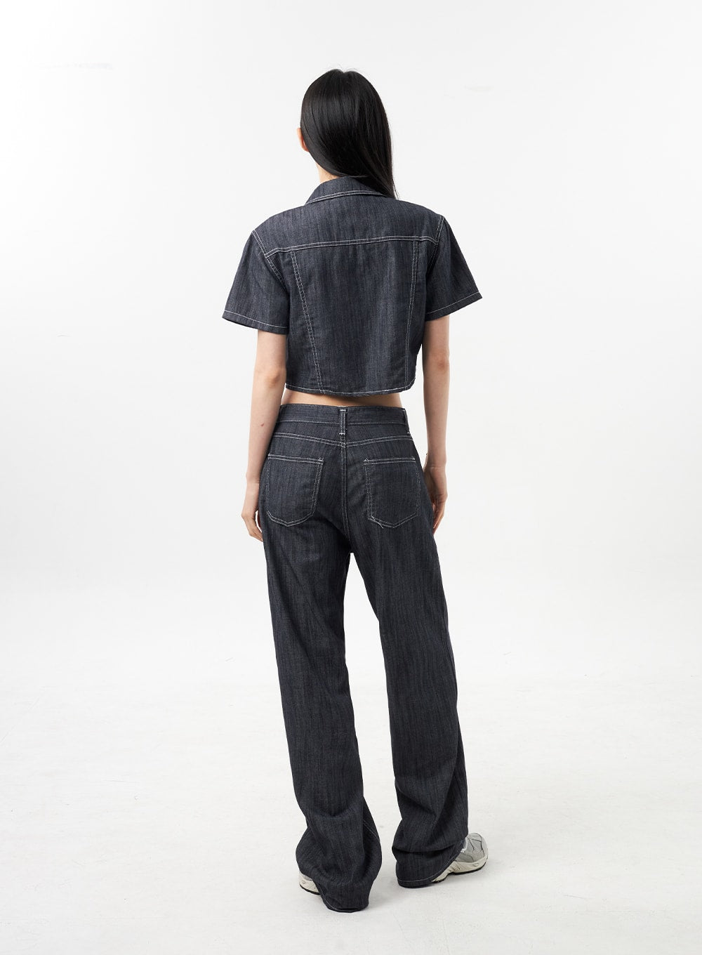 Low Rise Wide Pants CU312 in dark grey, full-length back view on model, back yoke and rear pockets with contrast white stitching, wide-leg hem pooling at sneakers, denim-on-denim styling.