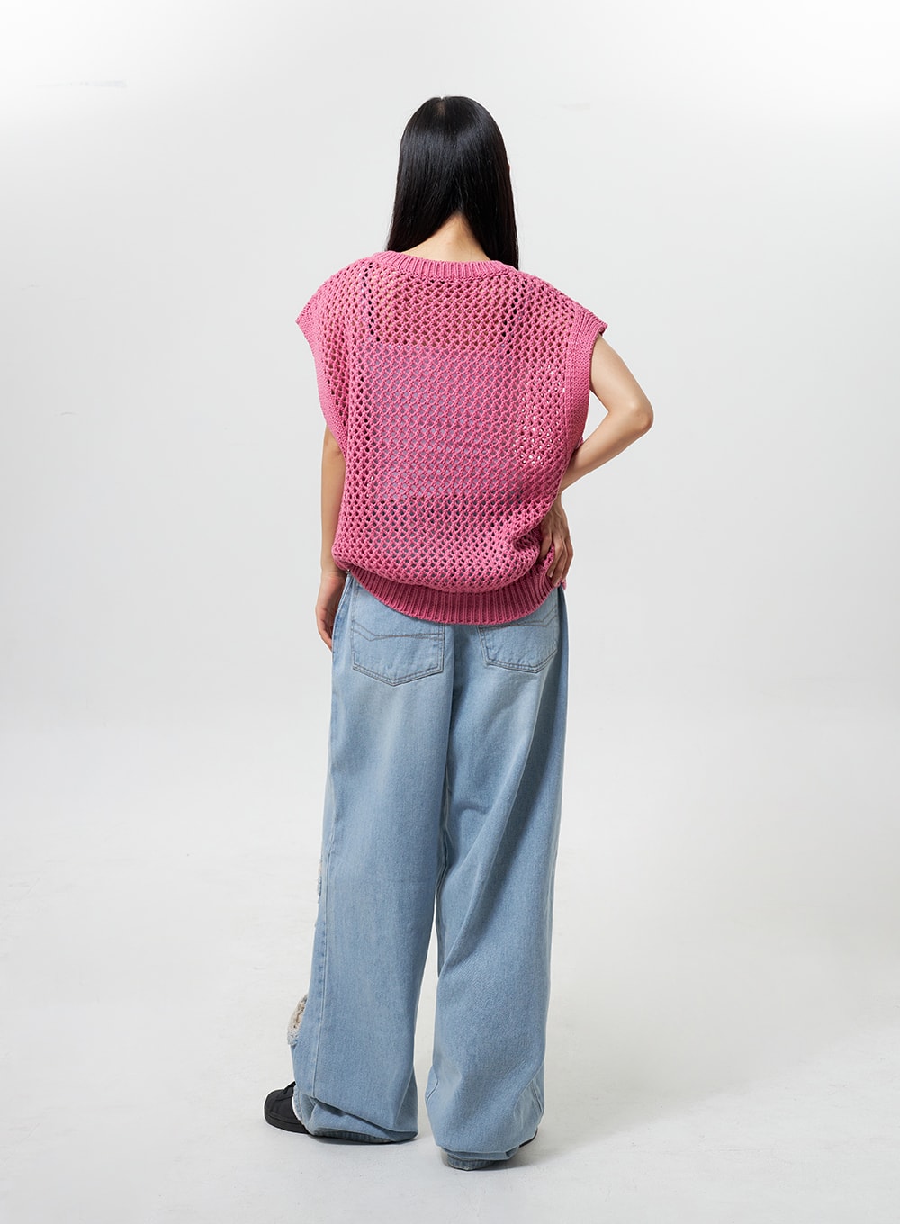 Oversized Ripped Jeans CY324 in light blue, full-body back view on model, wide-leg silhouette with back pockets and frayed rip visible near hem, paired with pink crochet vest.