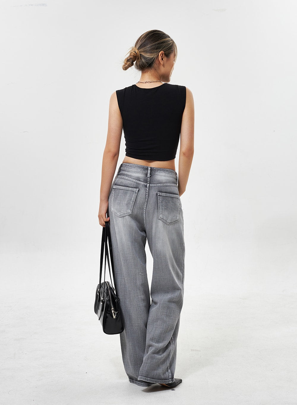 Mid-Rise Wide Leg Jeans CY330 in grey, full-length back shot on model, dual back patch pockets, faded wide-leg denim, styled with black crop top and bag.