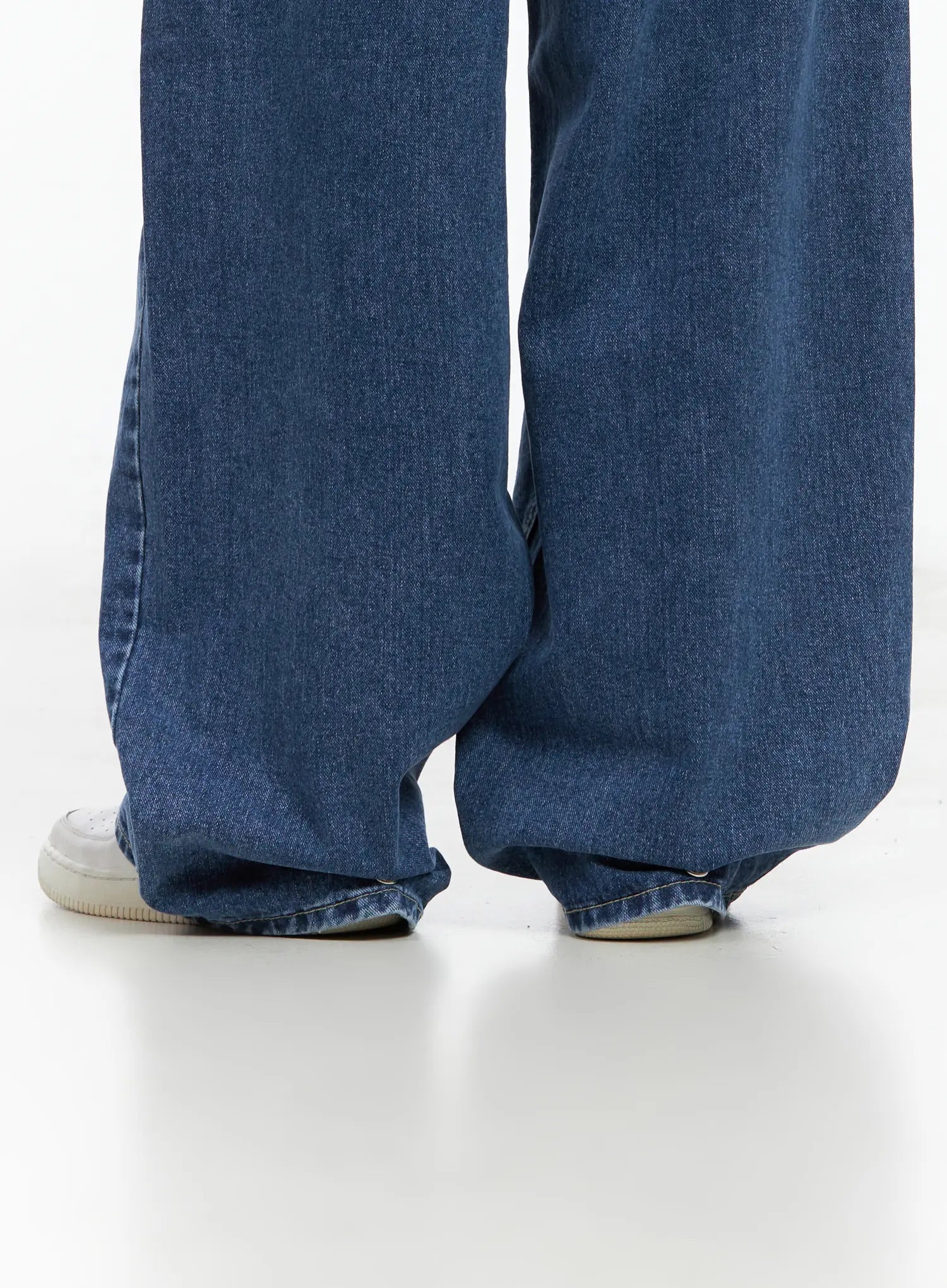 Hayoung Washed Wide-Leg Denim Jeans CL509 in dark blue, low-angle close-up of hem and leg opening on model, pooling wide-leg cotton denim over white sneakers, snap-button detail at cuff.