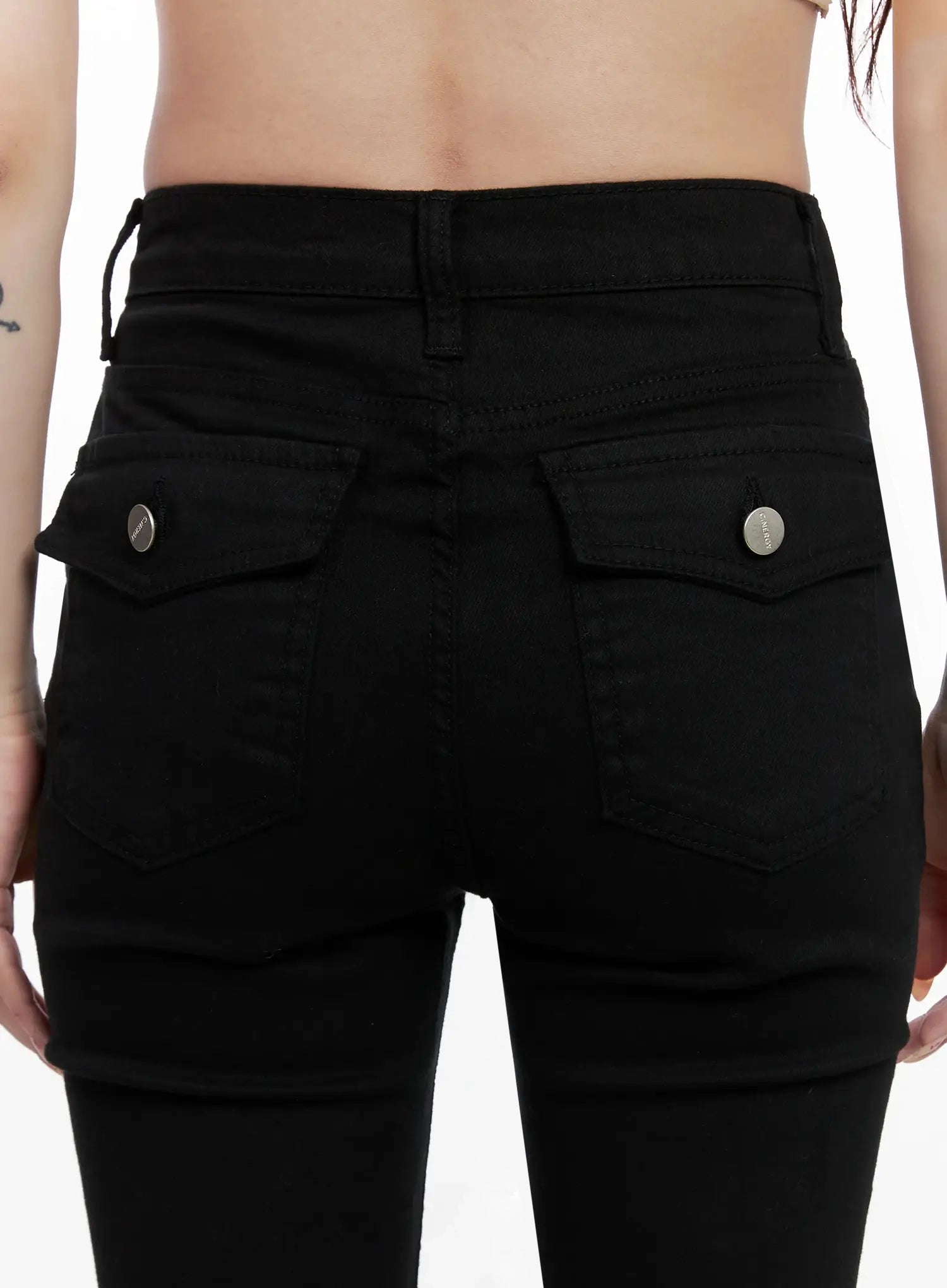 Dream Chic Black Flare Jeans IN514 in black, macro close-up of back waistband and pockets on model, dual snap-button flap pockets, belt loop, and stitching detail visible.